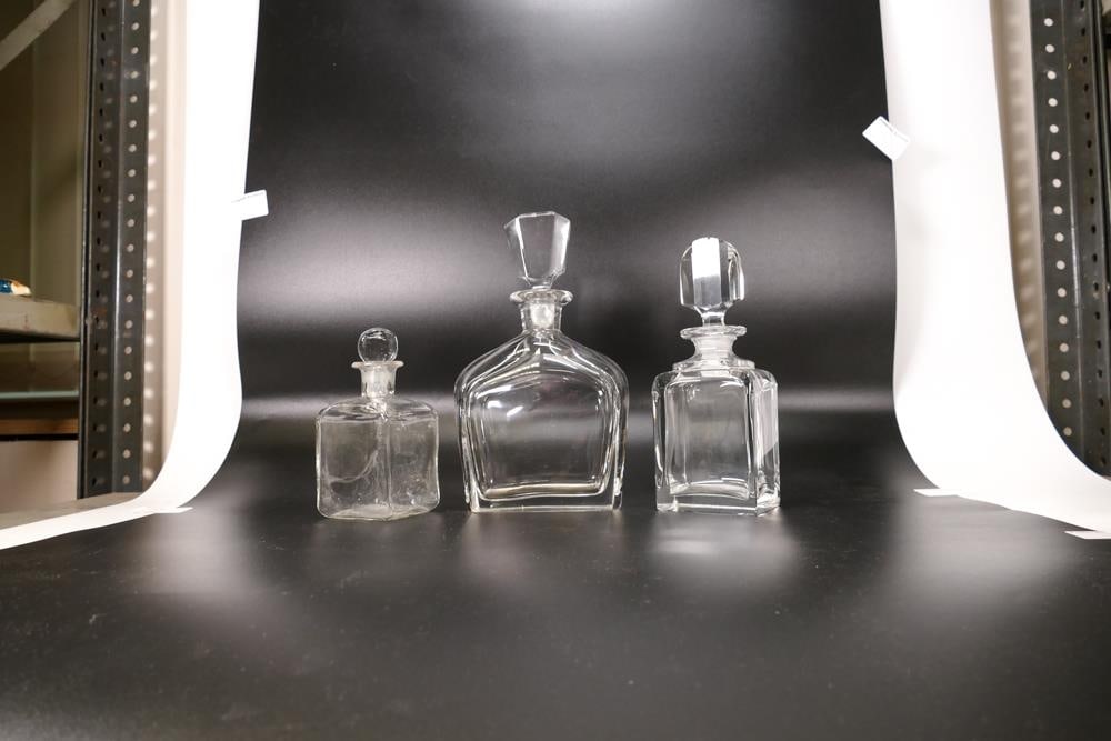 Three Glass Stoppered Bottles; to include two art deco large perfume bottles together with a smaller: Three Glass Stoppered Bottles; to include two art deco large perfume bottles together with a smaller rectilinear chemist bottle (3)