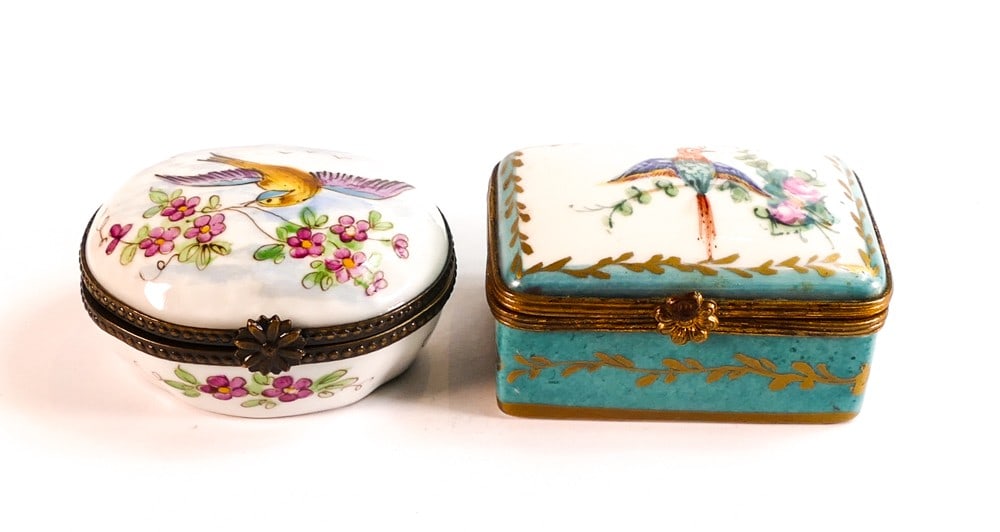 Two porcelain pill boxes set in metal hinged mounts. Both decorated with bird scenes. Size of: Two porcelain pill boxes set in metal hinged mounts. Both decorated with bird scenes. Size of largest, Height: 6cm Width: 4.5cm (2)