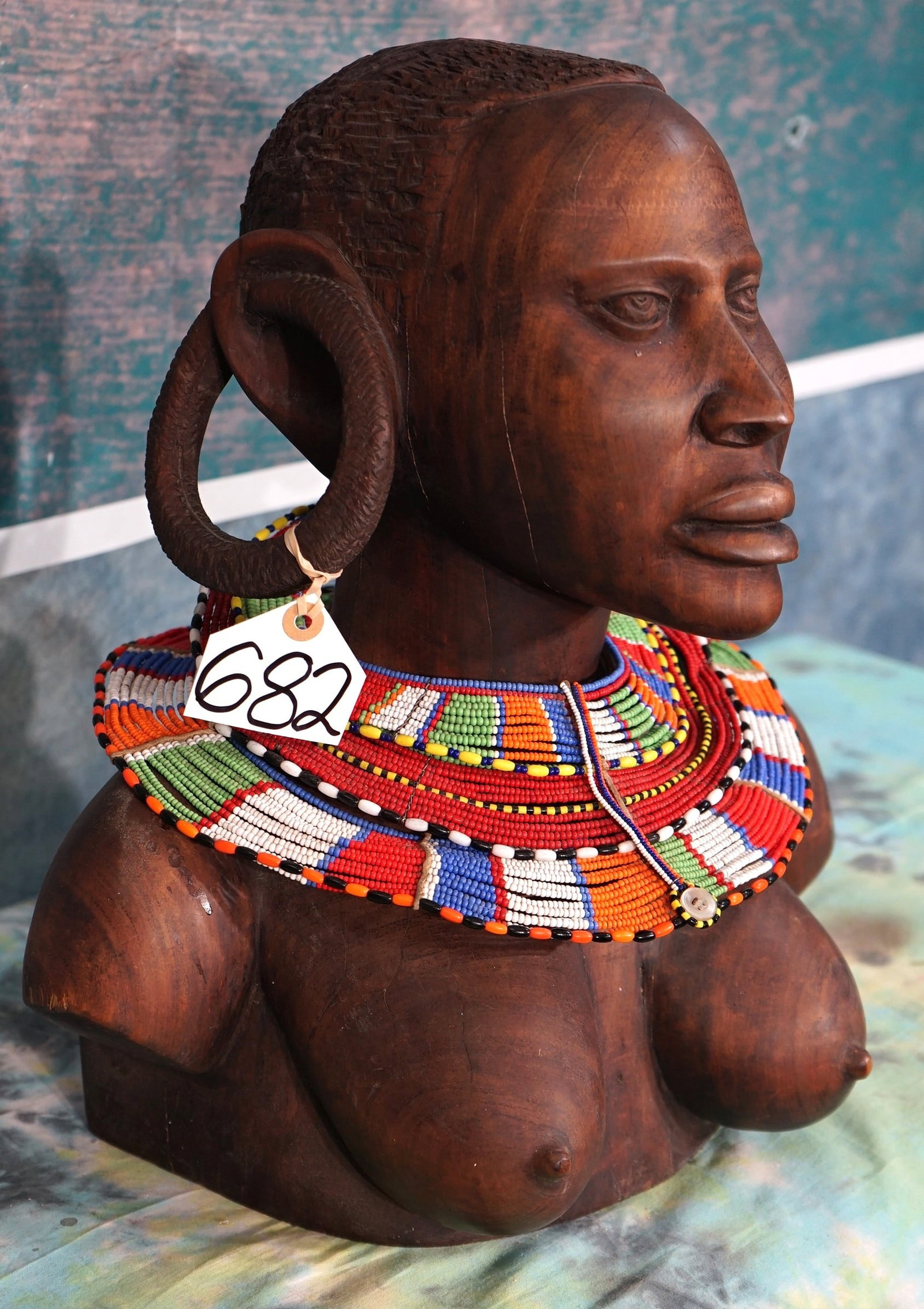 East African Wood Carved Masai Woman Shoulder Bust with Beautiful Handmade Tribal Necklace: This shoulder and head bust was carved from ironwood. The colorful beaded necklace is strictly a Masailand Tribal design. This carving is a true piece of East African Art.