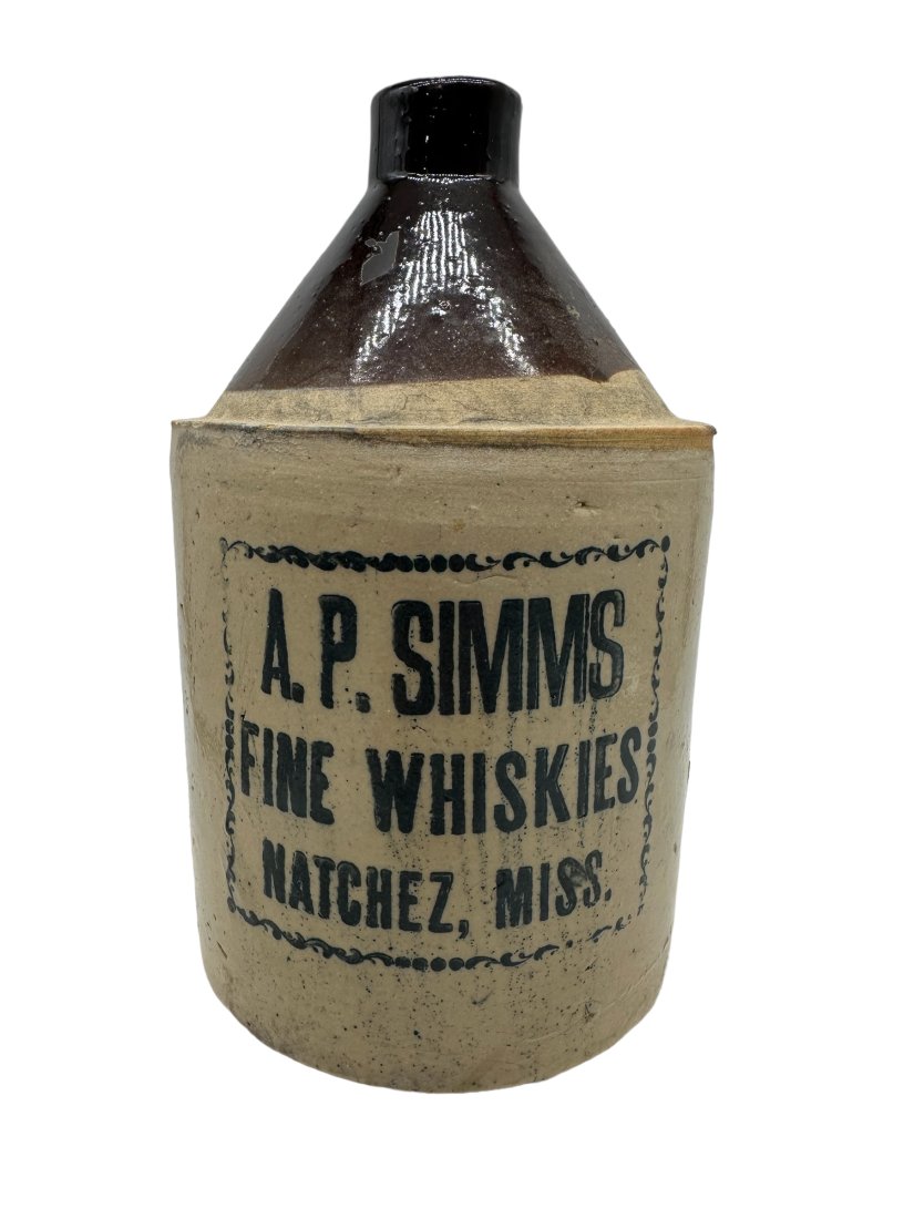 A.P. Simms Fine Whiskies Natchez Miss. Jug: Measures 9.5 inches tall. Small chip on lip. Chips on rim. No cracks.