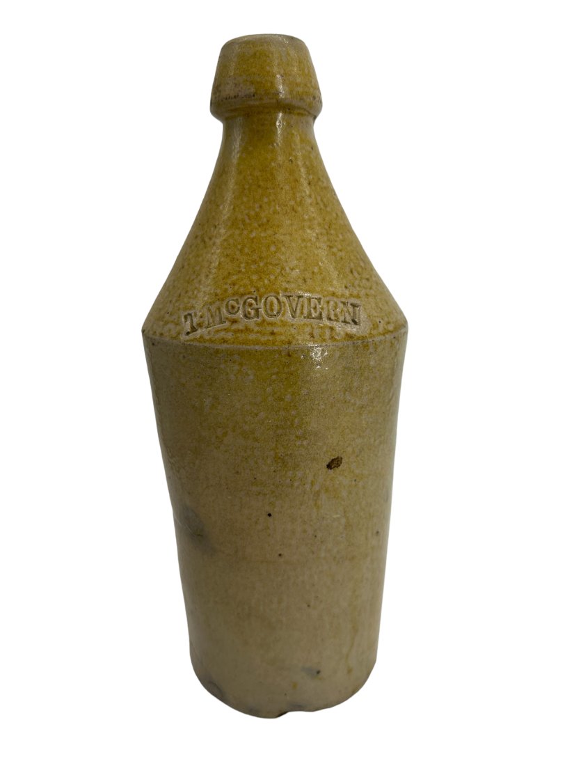 Stoneware Bottle T. McGovern: Chip on lip and rim. Measures 11 inches tall.