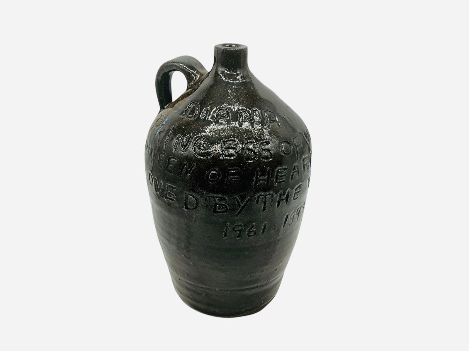 Grace Nell Hewell Princess Diana Tribute Jug: Mint condition. Signed, dated and phone number on bottom. Incised on body reads, "Diana Princess of Wales, Queen of Hearts, Loved by the World. 1961 - 1997." Measures 10.5" H x 6.5" L x 6.5" W.