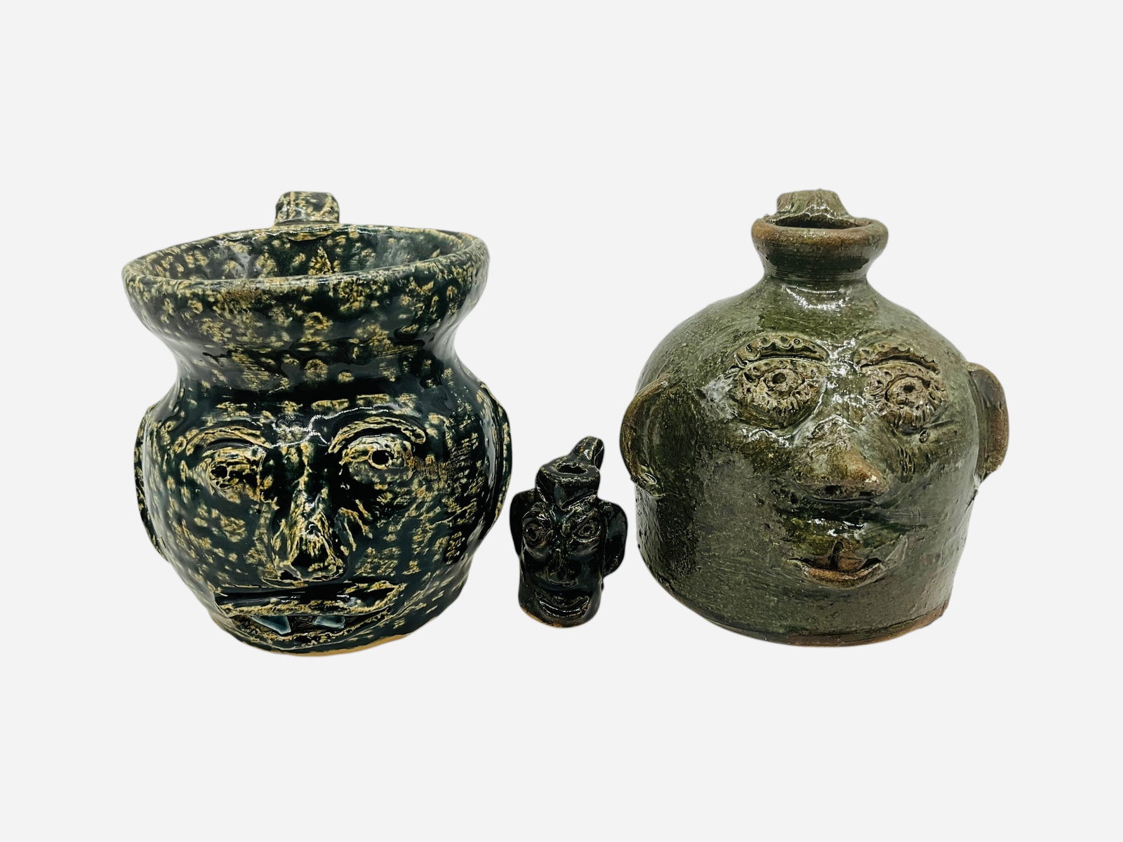 Three Small Works - Bobby & Chris Ferguson: Three small pieces total. All in mint condition and signed. Two small face jugs by Chris Ferguson and one mini face jug by Bobby Ferguson. Face pitcher and face jug by Chris stand 3.5 inches tall.