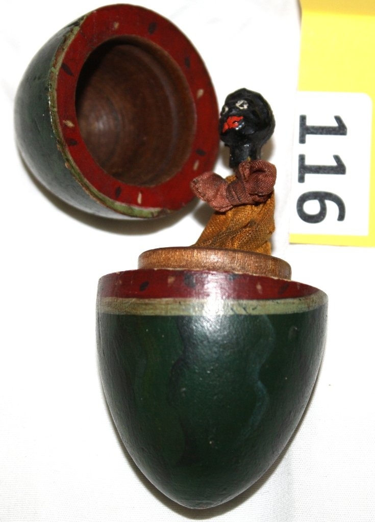 FOLK ART BLACK POP OUT TOY: BLACK FOLK ART POP OUT TOY, EGG SHAPED COLORED LIKE WATERMELLON WITH FOLK ART DOLL POPPING OUT OF CENTER WHEN OPENED, MINOR PAINT WARE