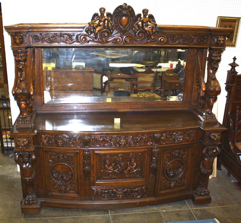 CARVED VICTORIAN OAK SIDEBOARD: LARGE MAGNIFICENT CARVED OAK SIDEBOARD, DECORATED WITH CARVED CUPIDS AND WINGED GRIFFINS, MEASURES 84'' WIDE X 82'' HIGH, HAS BEEN CUSTOMIZED WITH AN ADDITIONAL STORAGE SPACE CONSTRUCTED BEHIND MIRROR