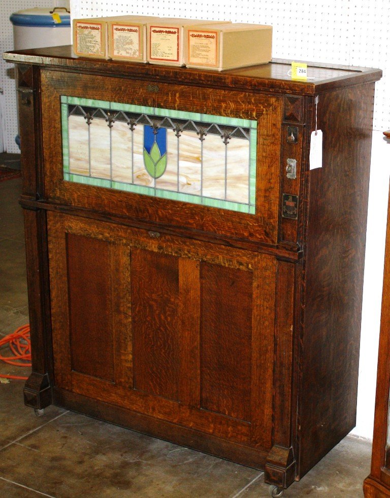 NICKELODEON: NICKELODEON IN QUARTERSAWN OAK CASE A ROLL PIANO (3 EXTRA ROLLS)LEADED GLASS FRONT, PLAYING CONDITION AND GOOD OVERALL CONDITION, MEASURES 57'' TALL BY 50'' WIDE