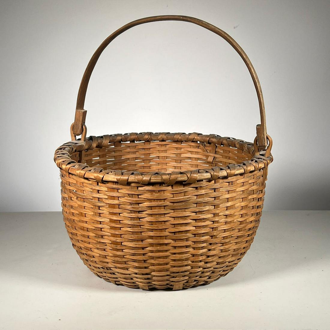 SPLINT APPLE BASKET: Vintage Basket of nice color with carved swing handle. - dia. 15.5 in. (Height excludes handle) Inventory Code: 1K-409 Provenance: Part of over six-hundred Items consigned from an important Millwood, 