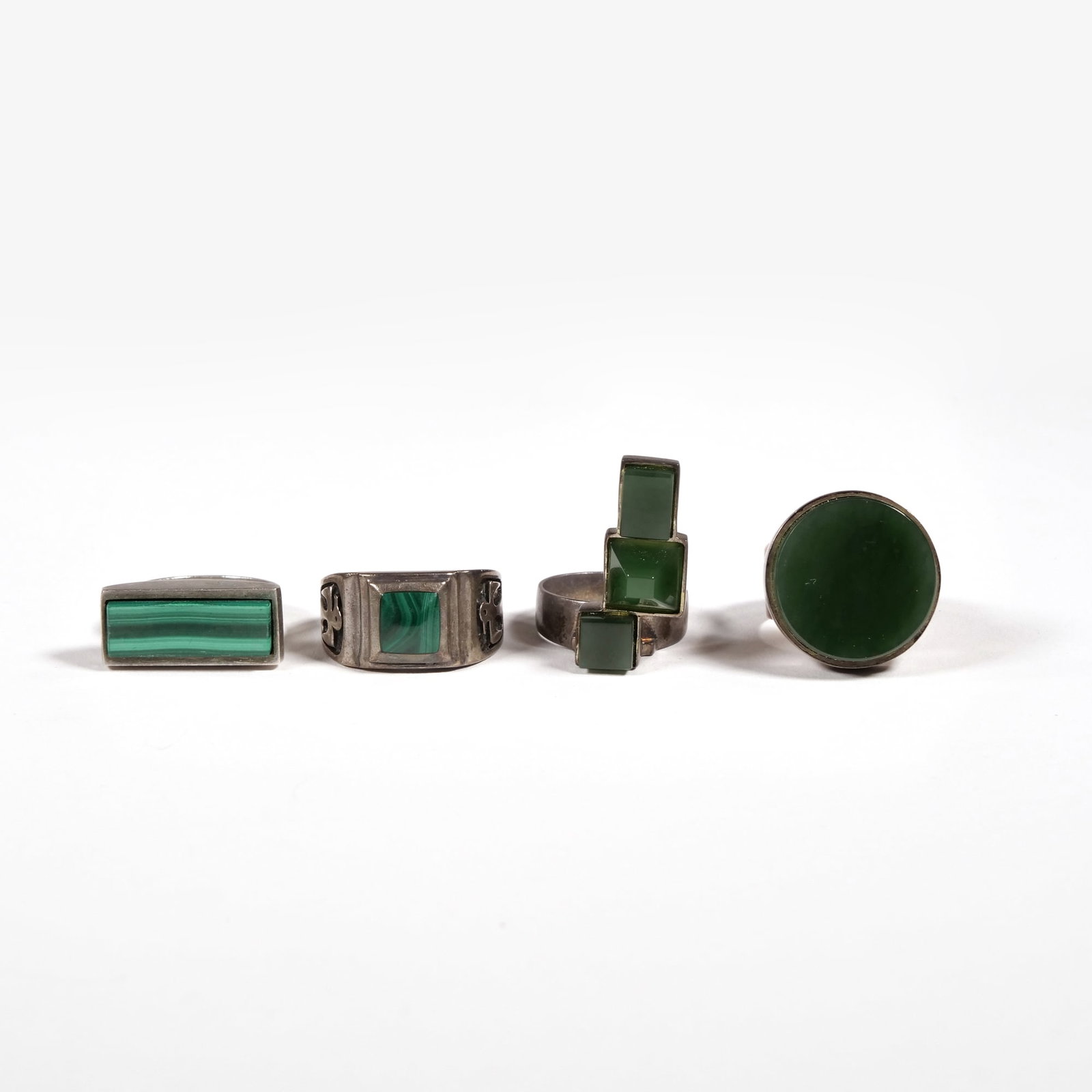 (4pc) STERLING RINGS: Including a malachite thunderbird ring, a ring with a bar of malachite, a ring with three semi-translucent green stones (not marked or tested), and a ring with a round semi-translucent stone; all toge