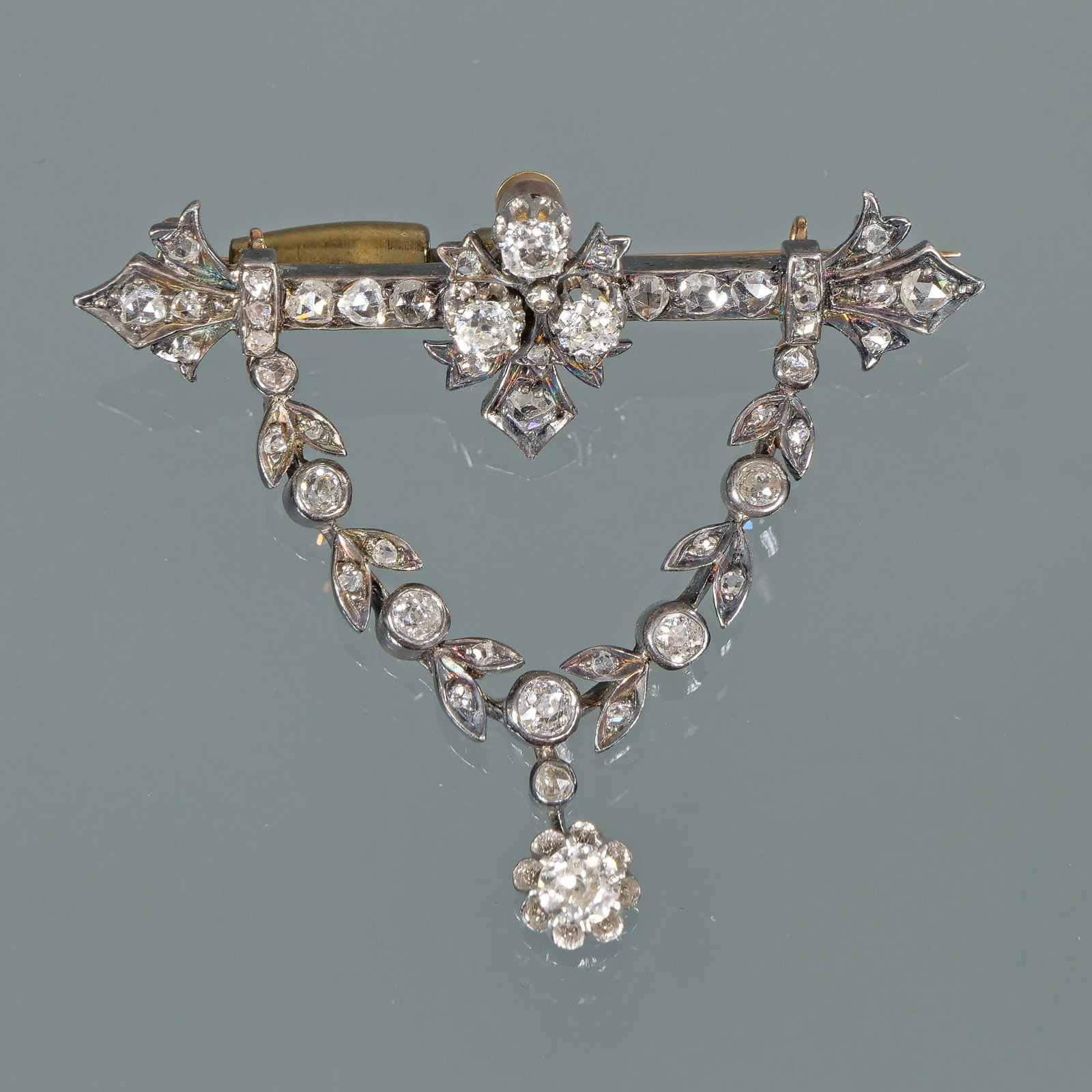 ANTIQUE LAUREL GARLAND BROOCH: 19th century, antique full cut and rose cut diamonds, designed as a bar-form pin mounting 27 diamonds suspending a laurel garland form section mounting 20 diamonds suspending a single diamond pendant 
