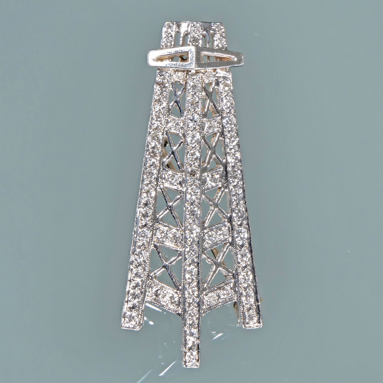 DIAMOND & PLATINUM OIL DERRICK PENDANT / PIN: Designed as a finely detailed oil derrick mounting melee diamonds with a pin back and loops for a chain; 1.5 in., 5.8g Provenance: From the estate of Scarsdale, NY lady Inventory Code: 4N-36