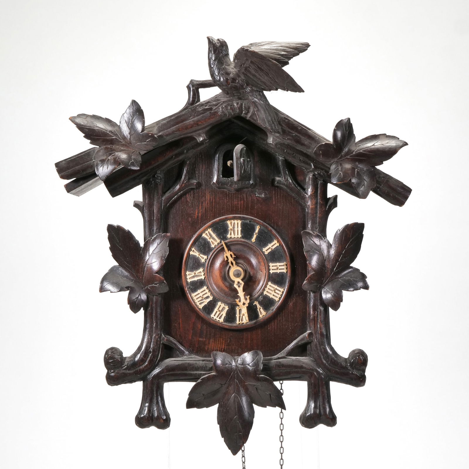 BLACK FOREST CUCKOO CLOCK: late 19th/ early 20th century, crested by a bird with maple leaves, with carved wood pendulum and carved bone hour and minute hands, with pine cone-form weights h. 23 x w. 15 x d. 7 in. Provenance: Fr