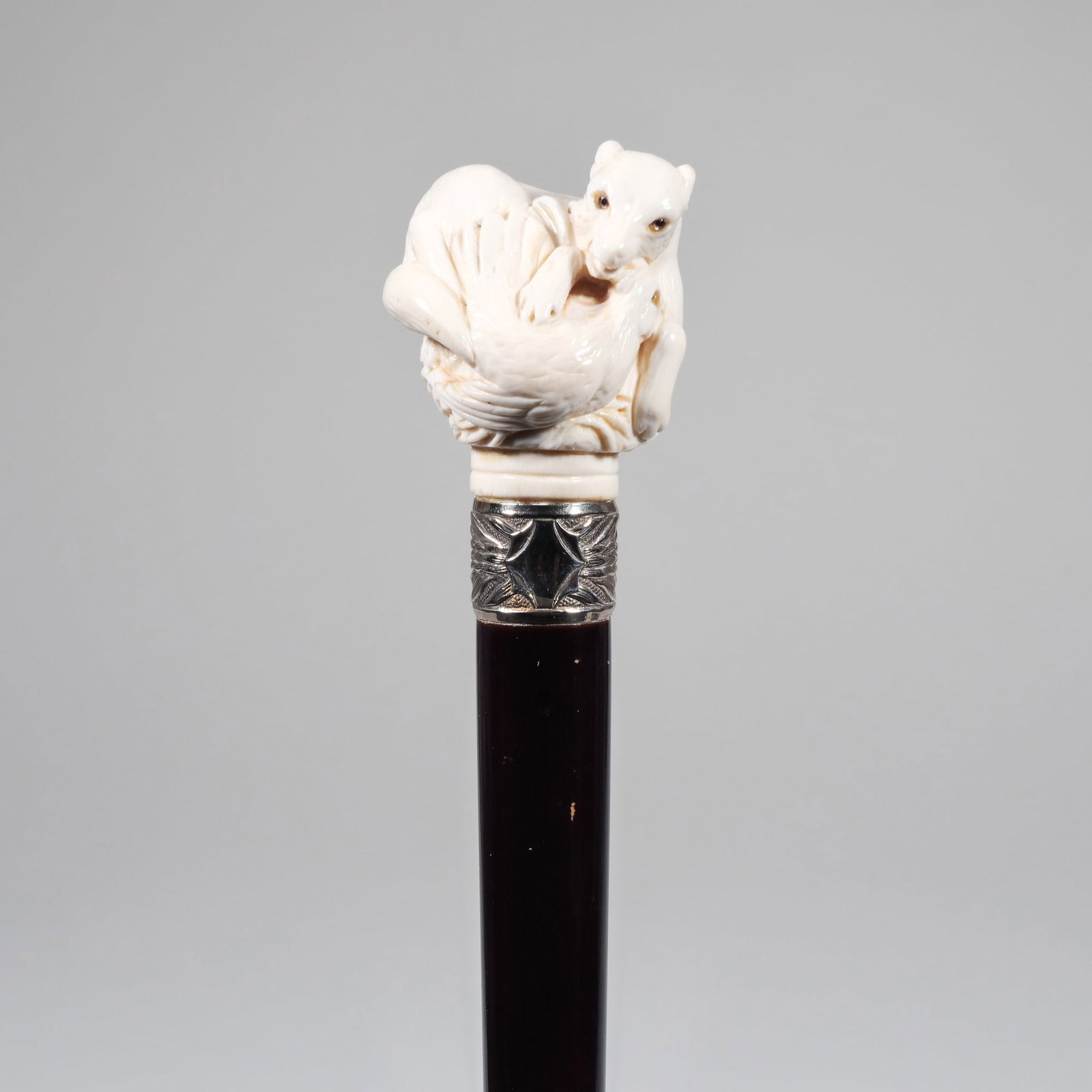 ANTIQUE CARVED BONE FIGURAL GROUP WALKING STICK / CANE: Showing a fox (or dog) curled around a chicken, with glass eyes, joined to the cane by a silver collar (no marking), lacquered wooden shaft, horn ferrule l. 35 x d. 2 x dia. 2 in. Provenance: Items fr