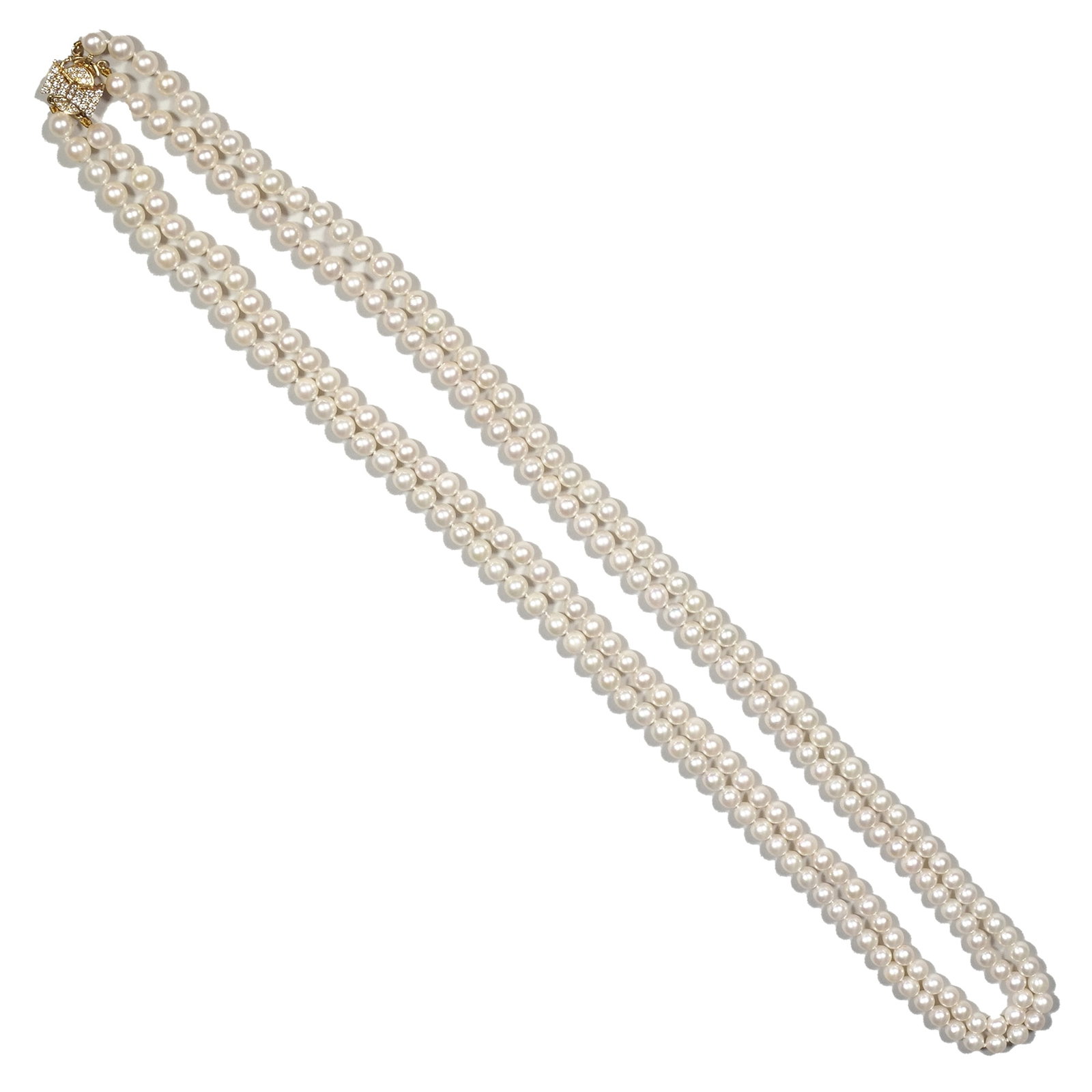 14K & DIAMOND BOW-CLASPED PEARL NECKLACE: Designed as a 14k yellow gold diamond-encrusted clasp with central diamond bow-form motif suspending two strands of hand-knotted pearls of well-matched size and color, the clasp with fineness mark; 13