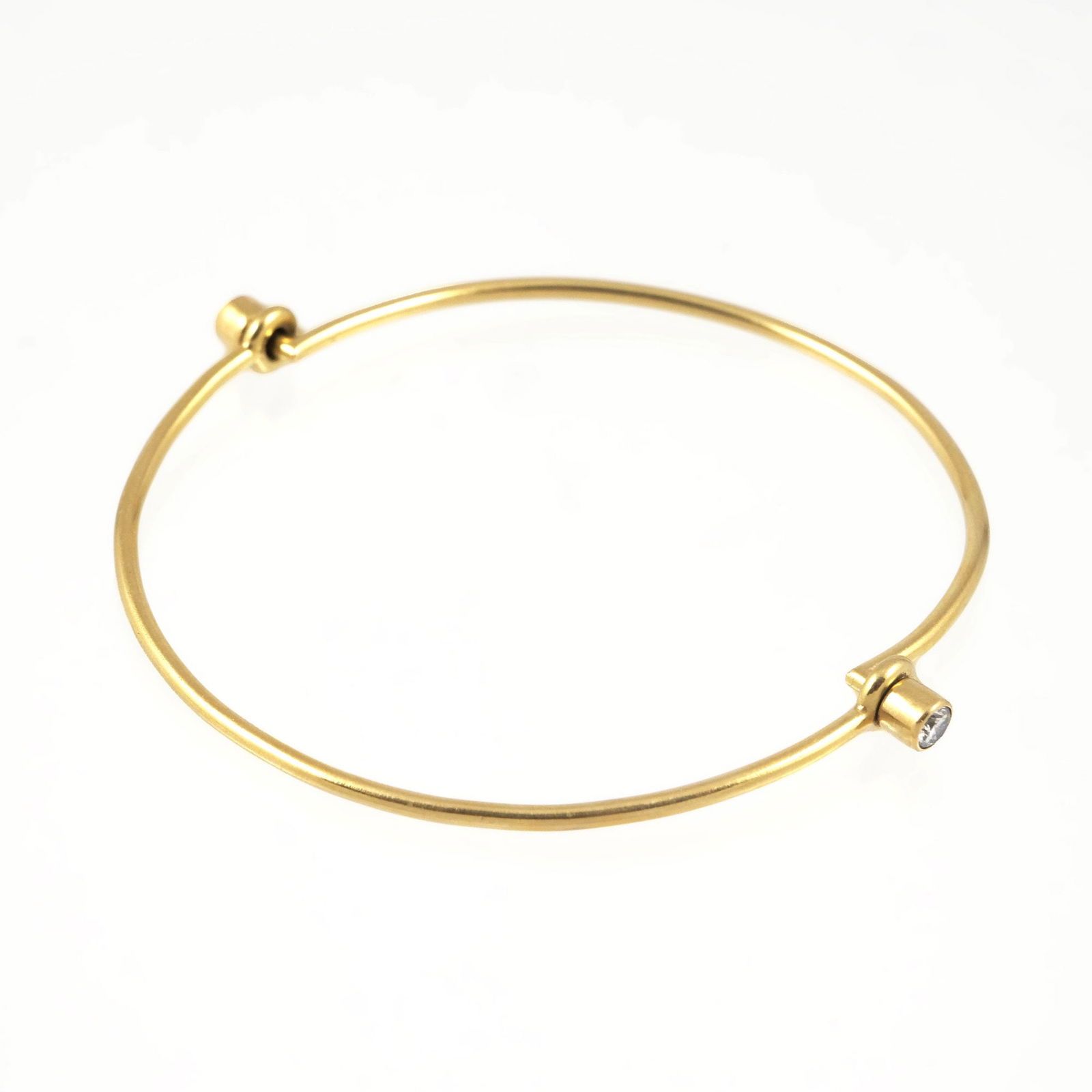 18K GOLD & DIAMOND WIREWORK BRACELET: 18k yellow gold bracelet having two articulating hinges each mounting a single diamond (bracelet folds in half), internal diam. approx. 2.5 in.; no apparent fineness mark, tested to 18k gold; gross we