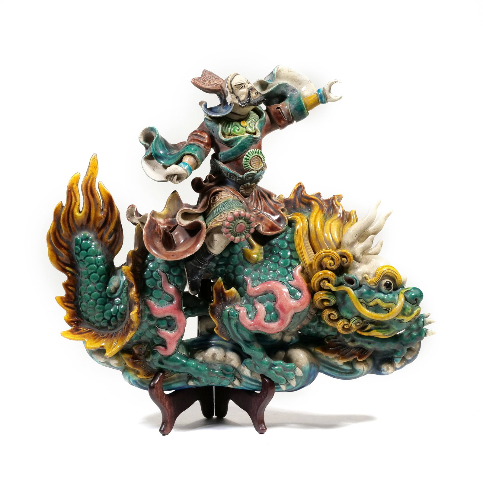CHINESE SHIWAN SANCAI GLAZED POTTERY FIGURE OF A WARRIOR RIDING A QILIN: Sancai-glazed ceramic figurine depicting a warrior in traditional armor riding a scaled mythical beast atop a cloud-form base. The color palette features vibrant green, yellow, and manganese glazes