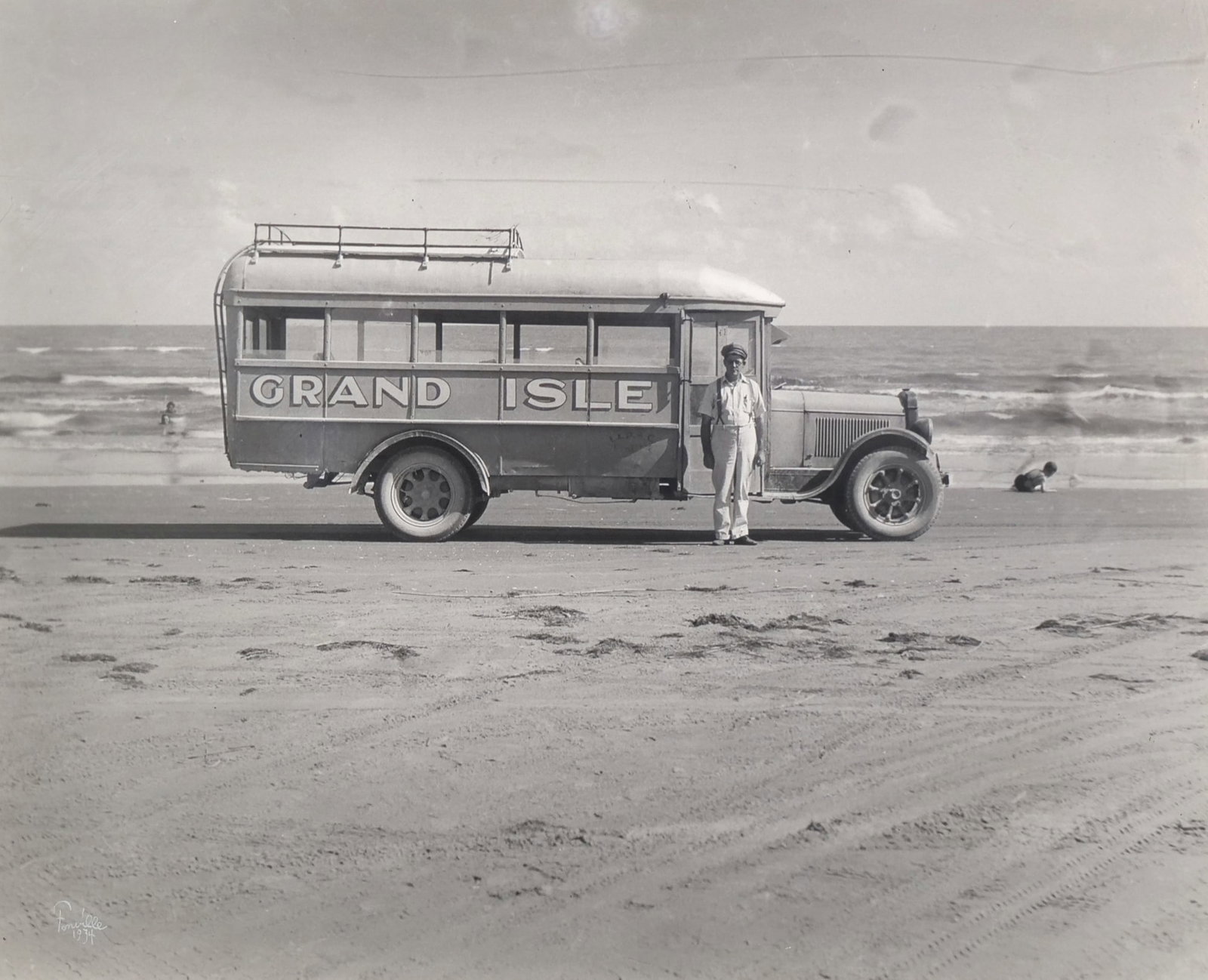 THEODORE FONVILLE WINANS (AMERICAN, 1911-1992) PHOTOGRAPH: Grand Isle BusSilver gelatin photographSigned and dated lower left15.5 x 19.25 in. (sight) n.b.The image depicts a passenger bus parked on the beach of Grand Isle, Louisiana. Before a bridge was const