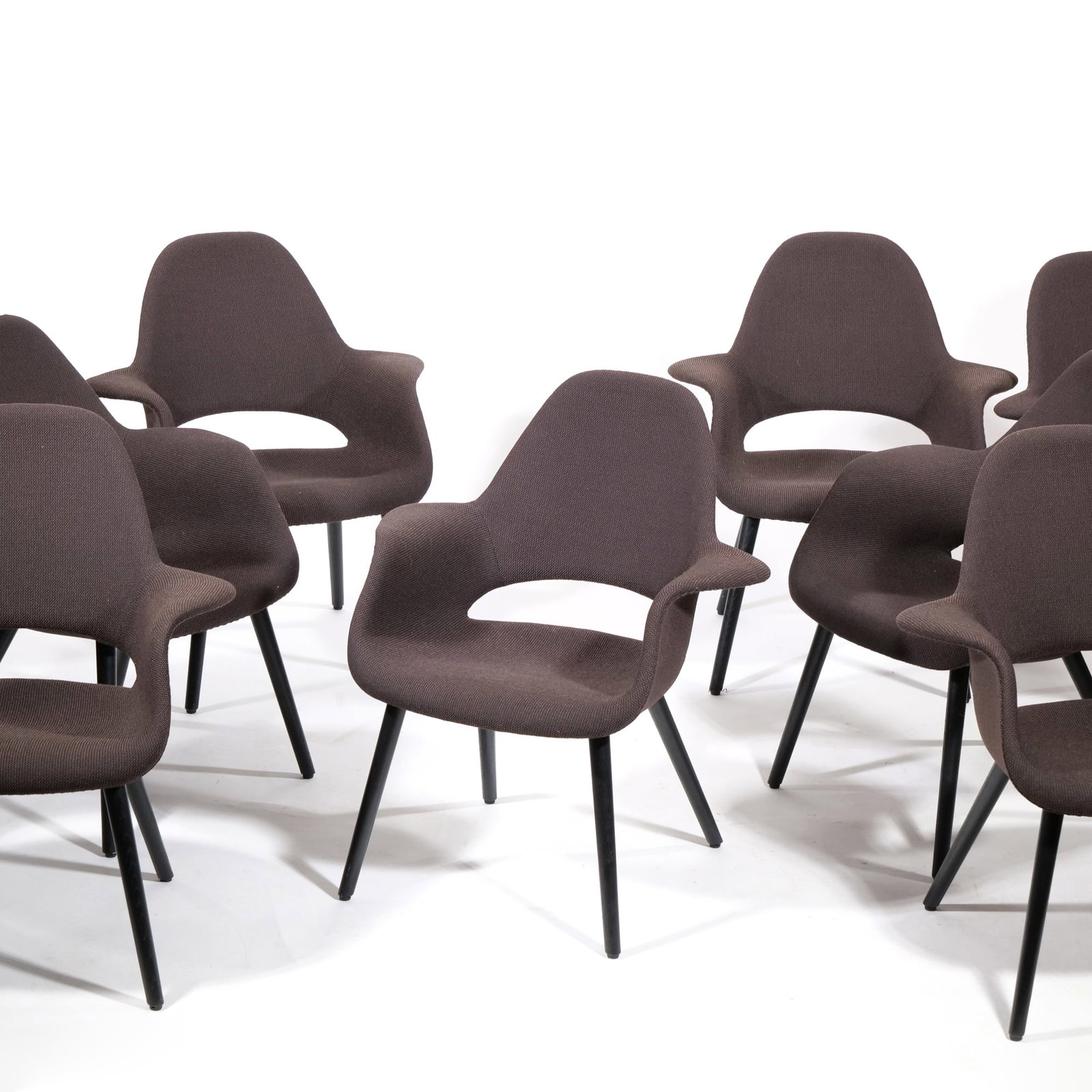 (8pc) SET VITRA ORGANIC CHAIRS BY CHARLES EAMES AND EERO SAARINEN: Set of eight upholstered dining chairs featuring a dark brown textured woven fabric and black tapered legs. The design includes an organic, contoured shell with a distinctive oval cutout at the base o
