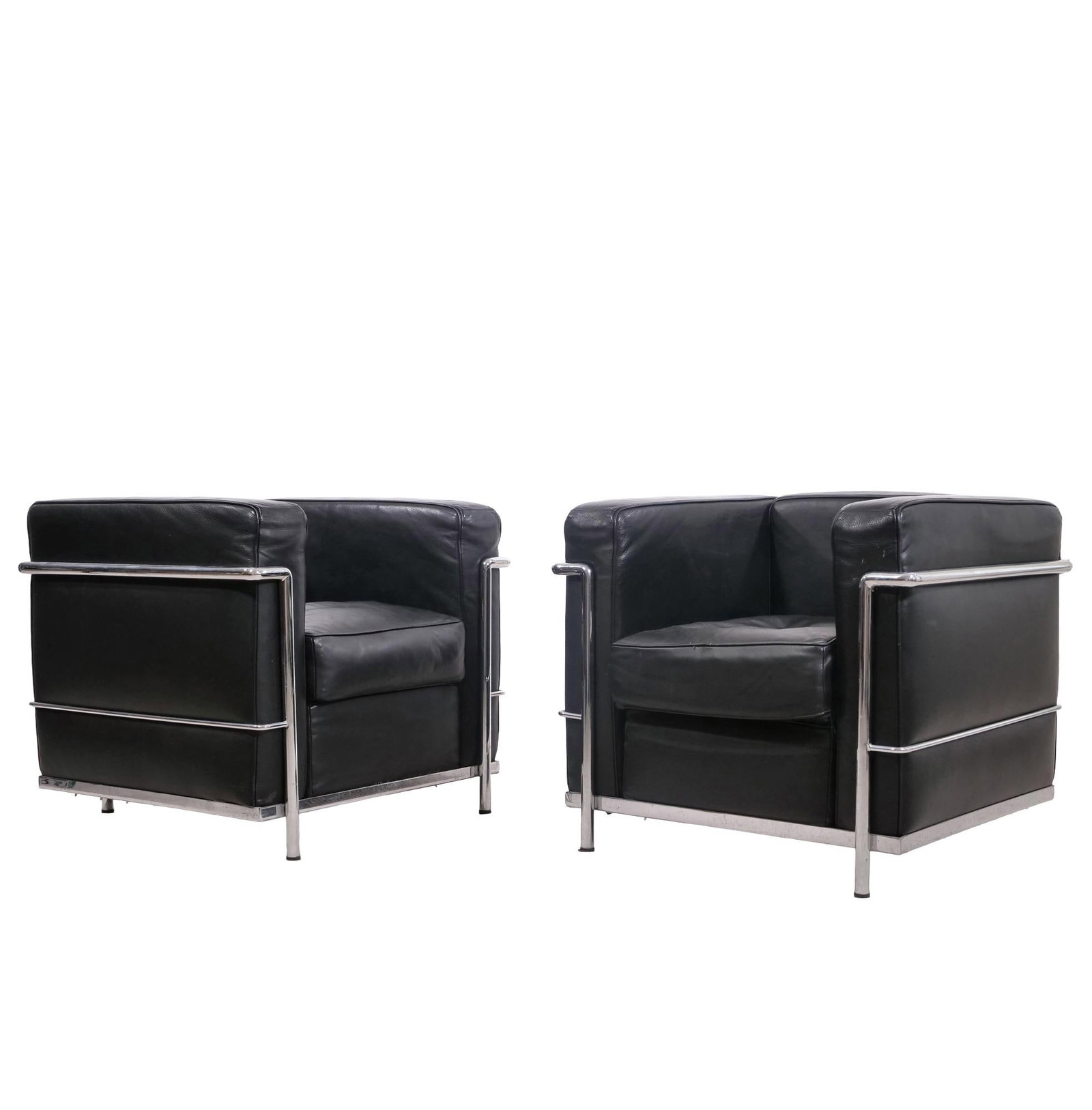 PAIR OF MILO BAUGHMAN STYLE BLACK LEATHER AND CHROME ARMCHAIRS, LC2 STYLE: Pair of cube-form armchairs upholstered in black leather with a tubular chrome-plated steel frame. Each chair features a wrap-around frame that supports the back, side, and seat cushions. The undersid