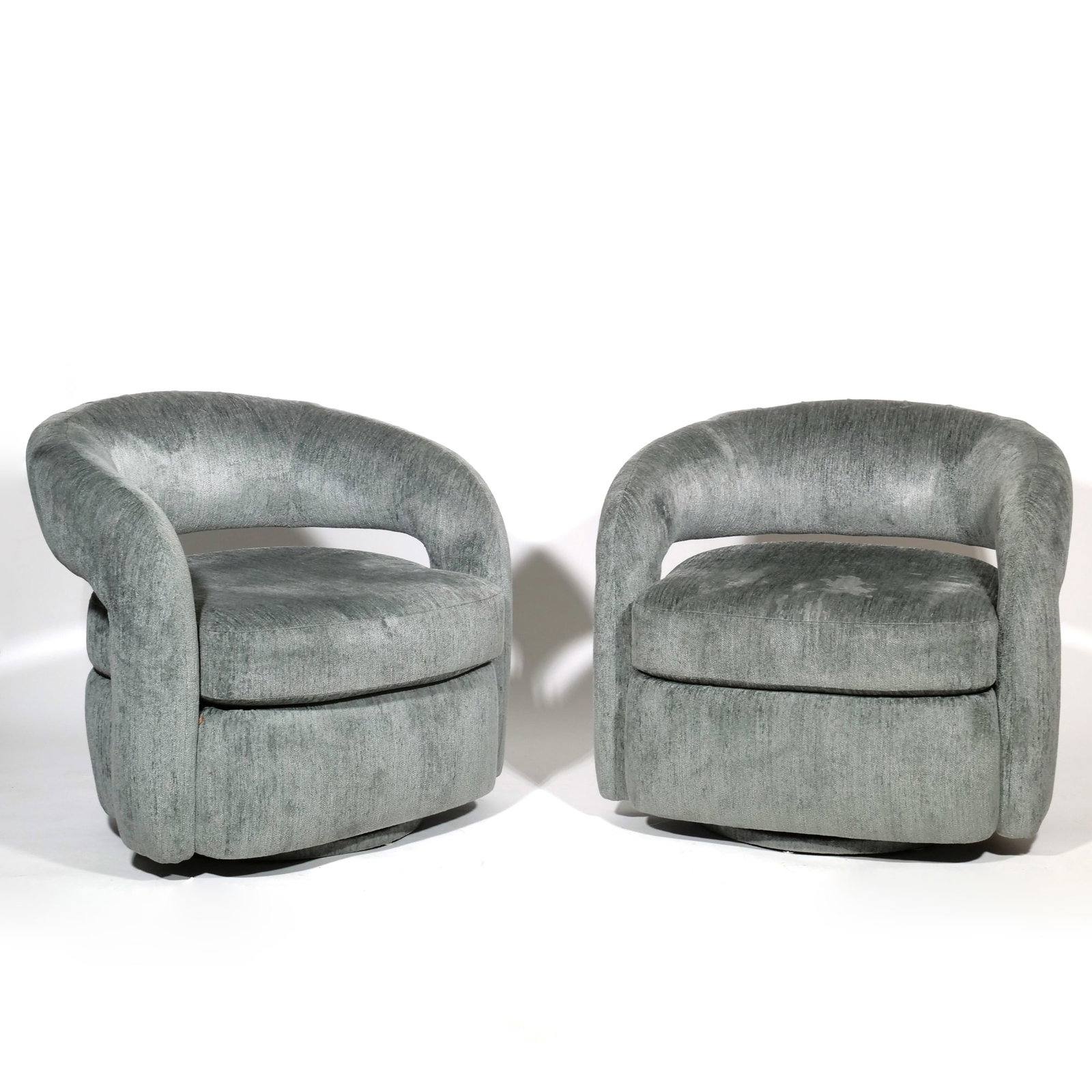 PAIR INTERLUDE HOME SWIVEL CHAIRS: Pair of barrel-back swivel armchairs upholstered in a textured grey fabric with horizontal backrest opening, each with a seat height of 18 inches. Built on fully upholstered bases with swivel mechanis