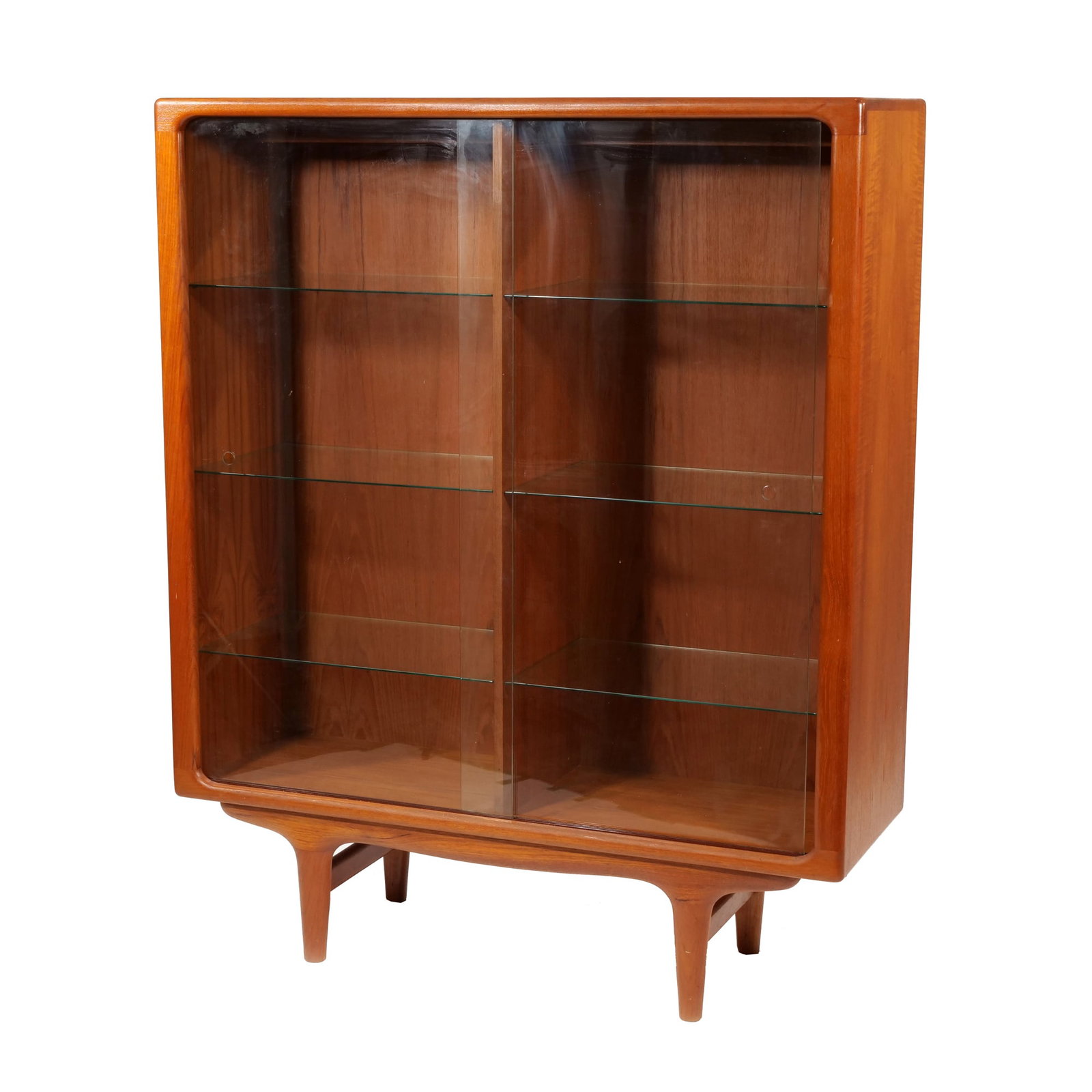 SILKEBORG DANISH MID-CENTURY MODERN TEAK DISPLAY CABINET: Teak construction featuring two sliding glass doors and six adjustable interior glass shelves, over a shaped stretcher base. The design features rounded frame corners and a recessed base with four tap
