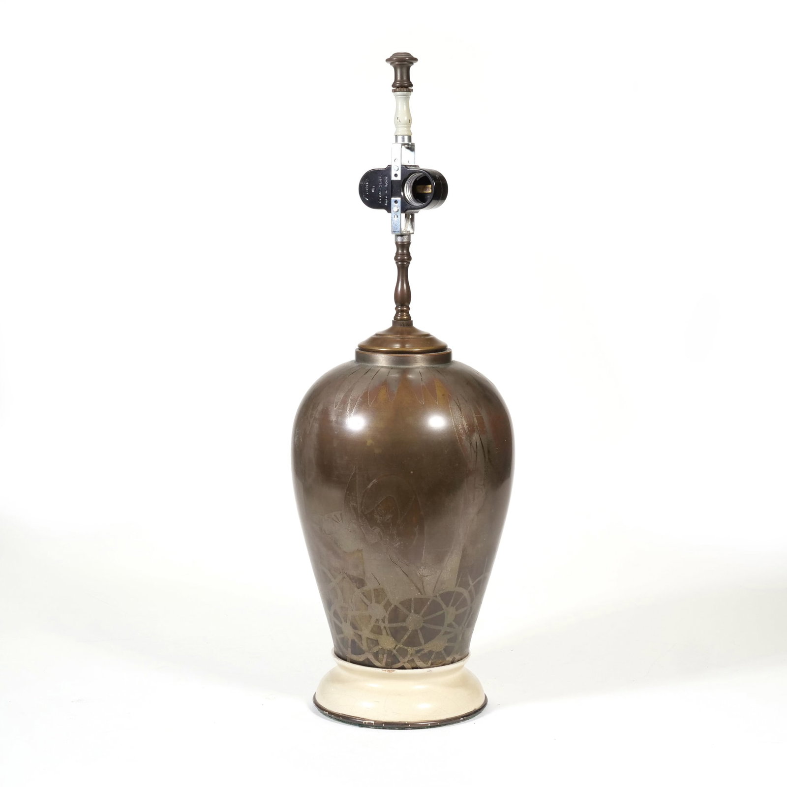 MID-CENTURY ACID-ETCHED BRASS URN-FORM TABLE LAMP: This mid-century table lamp features an urn-form metal body with a dark patinated finish. The body is decorated with an acid-etched design depicting a winged figure situated above a series of