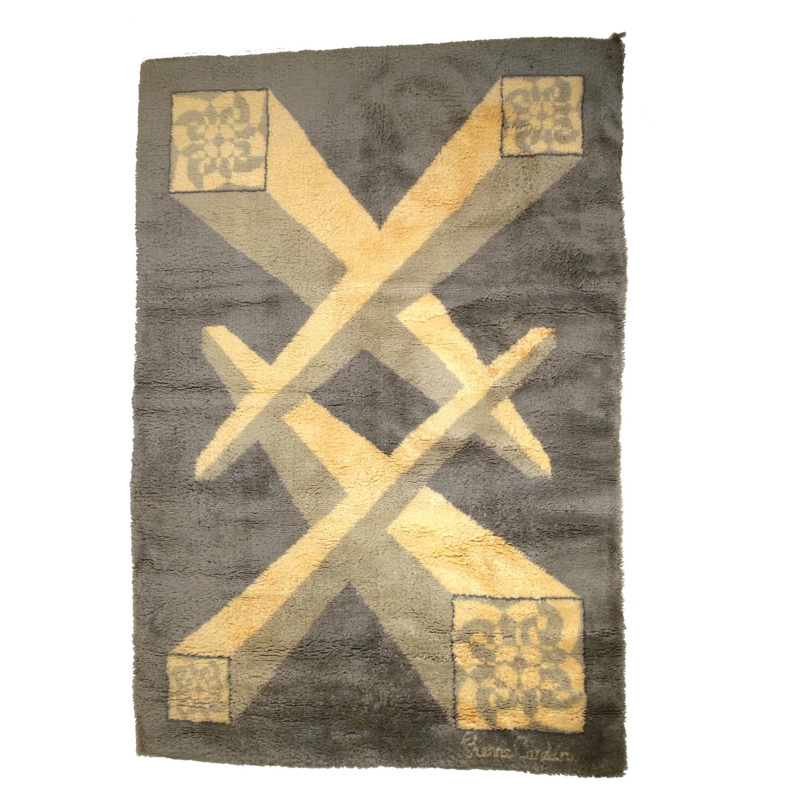 PIERRE CARDIN GEOMETRIC SHAG RUG: Circa 1970s, shag pile rug with a geometric design of interlocking diagonal beams in cream against a gray ground. The beams terminate in squares containing stylized floral motifs. Woven "Pierre