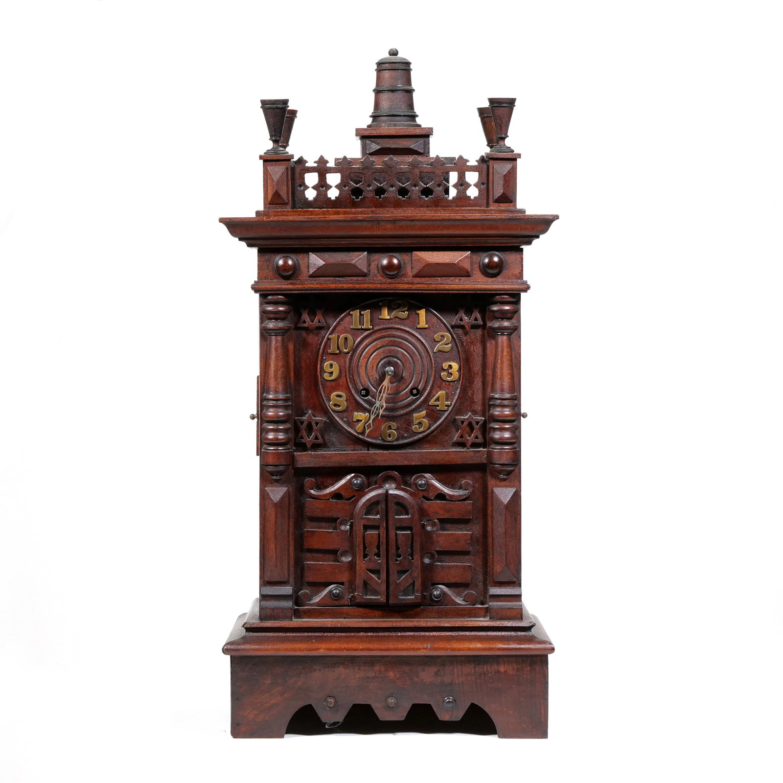 GERMAN BLACK FOREST WOOD TRUMPETER CLOCK: The dark-stained wood case features architectural detailing including fluted columns, a pierced top gallery, and turned finials. The wooden dial is decorated with concentric circular carvings, brass A