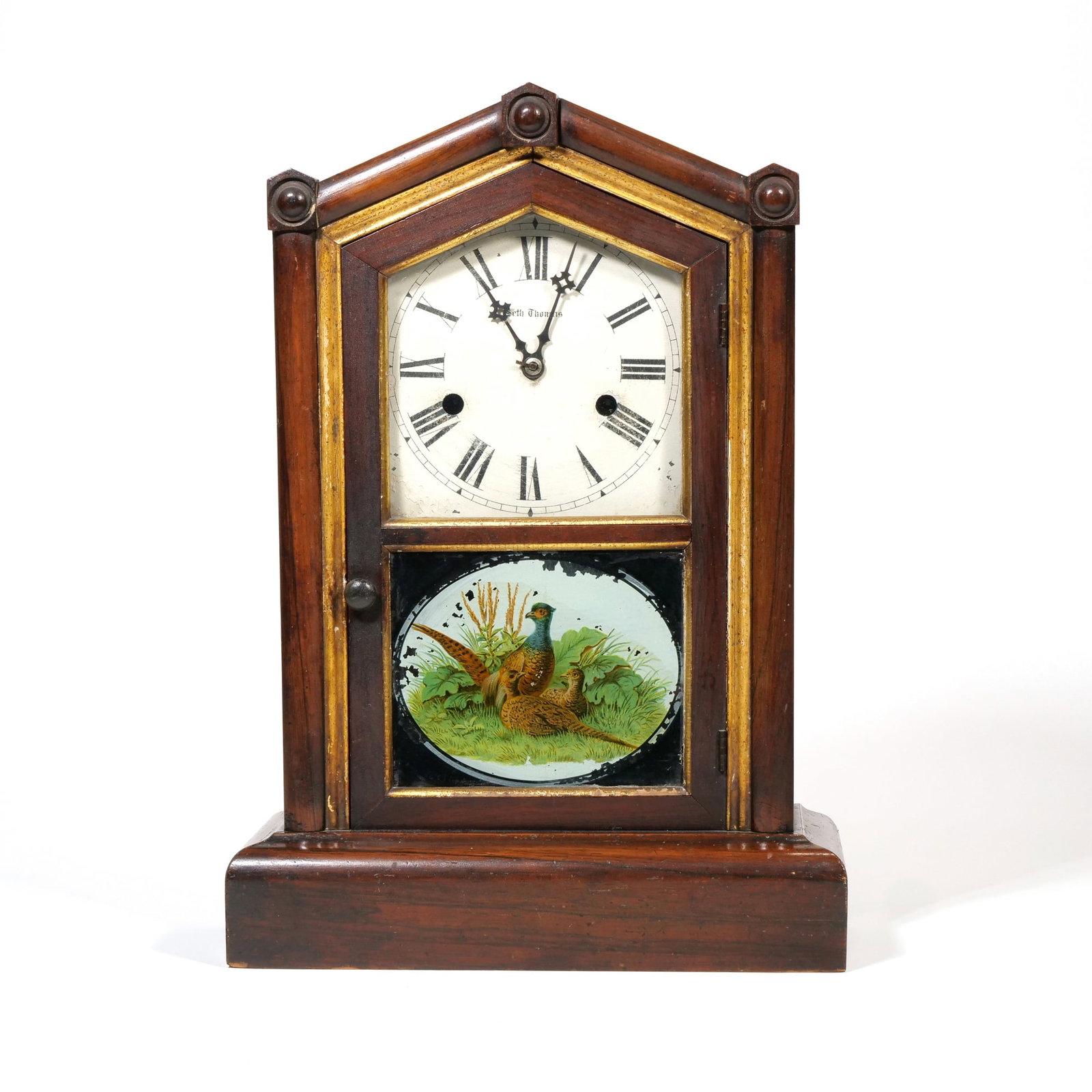 SETH THOMAS WOODEN STEEPLE CLOCK WITH REVERSE PAINTED PARTRIDGE PANEL: This wooden mantel clock features a pointed gabled top and gold-toned decorative trim surrounding the dial and lower tablet. The painted metal dial displays black Roman numerals and the manufacturer's