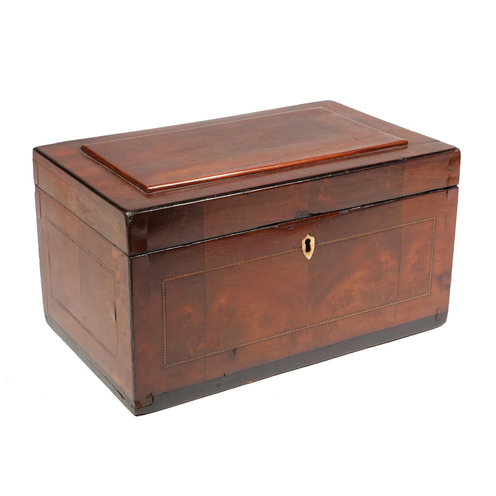 19TH CENTURY MAHOGANY & INLAID TEA CADDY: Rectangular mahogany box with flame grain veneers and light-colored inlaid stringing in a chevron pattern. The front is centered by a shield-shaped escutcheon and contains a lock mechanism with an acc