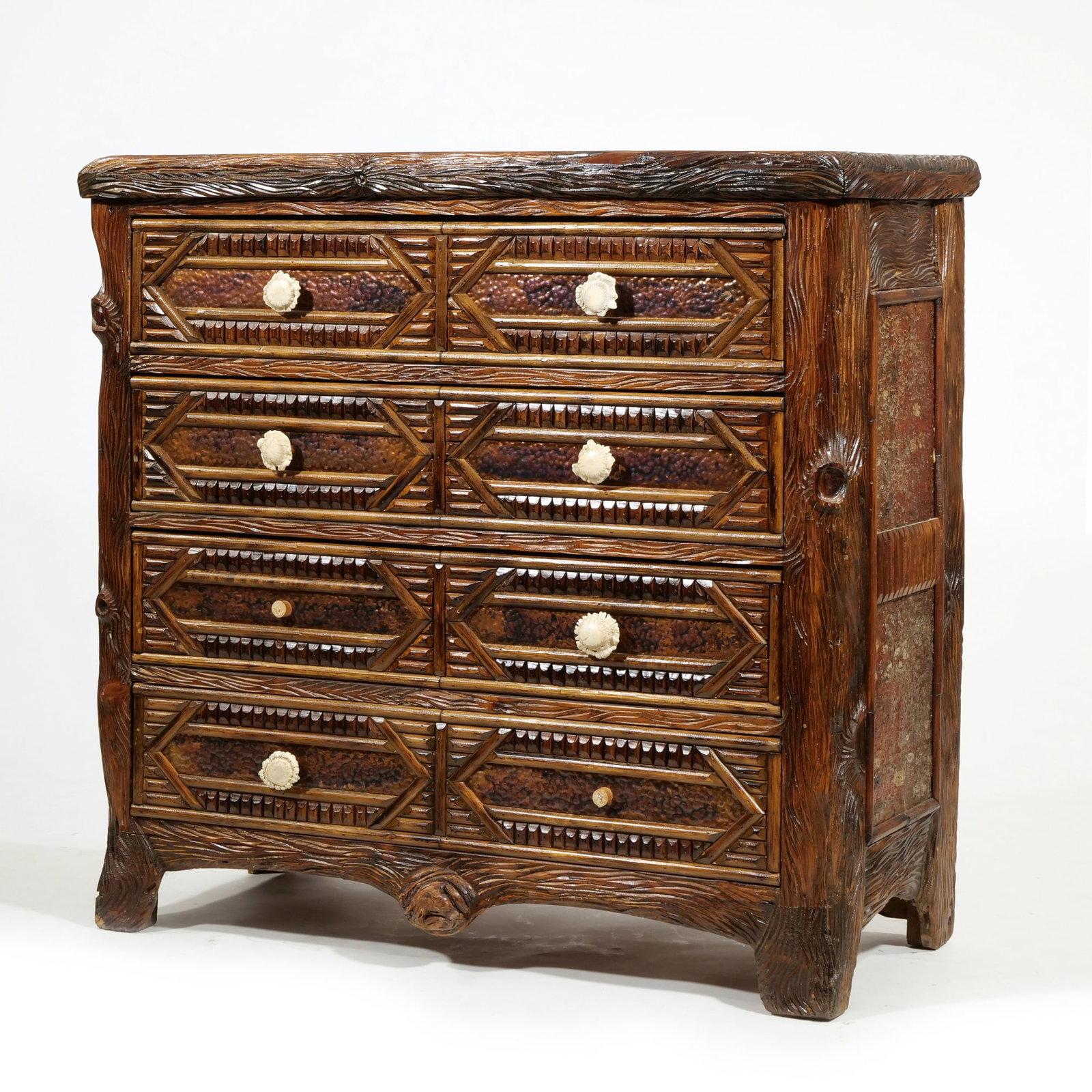 DWAYNE R. THOMPSON ADIRONDACK FOUR-DRAWER CHEST: Four-drawer chest in the Adirondack style featuring elaborate faux-bois and geometric carvings. Each drawer front contains two octagonal panels with textured centers and carved floral knobs. Signed