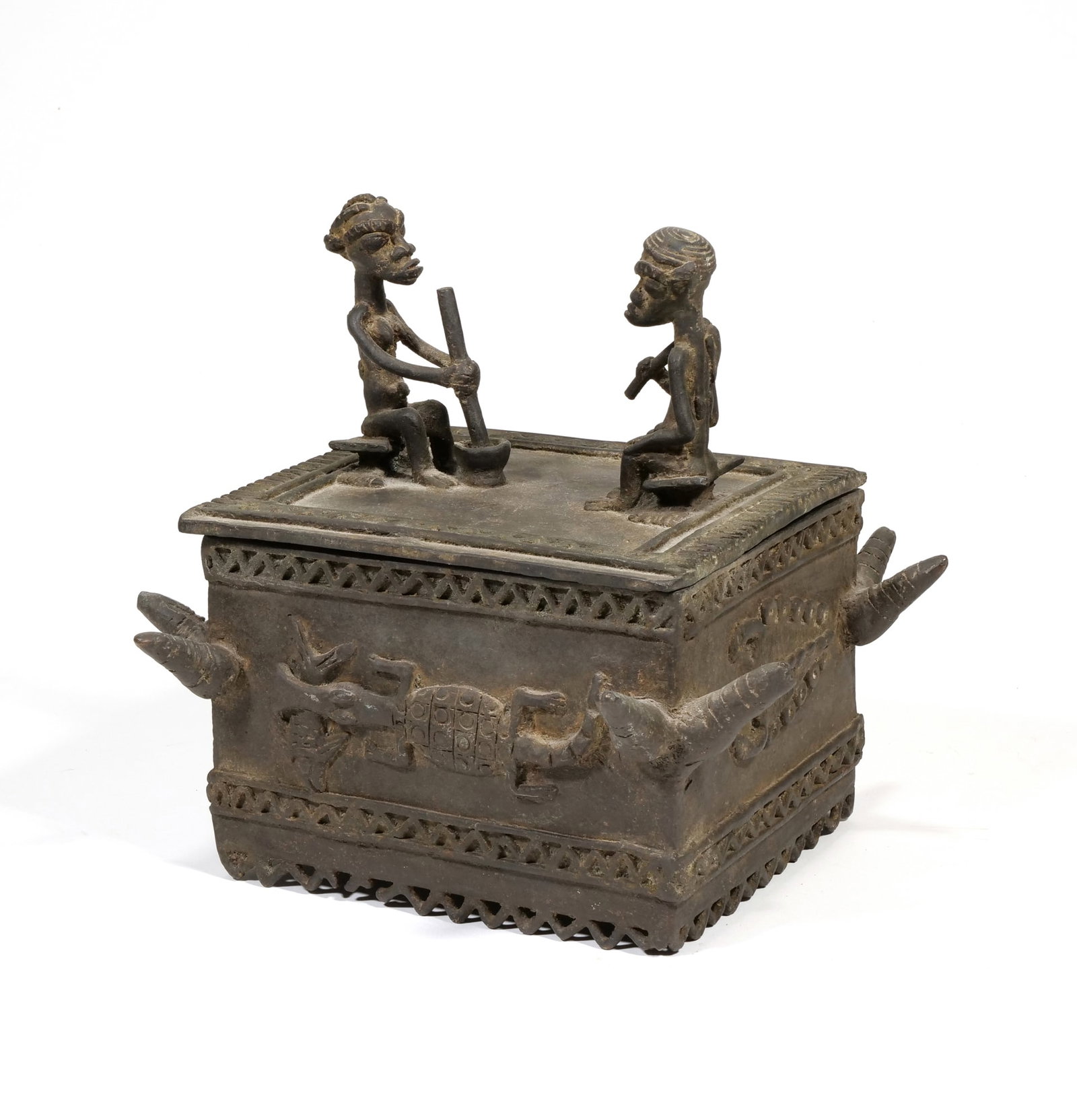 WEST AFRICAN CAST METAL RITUAL BOX WITH FIGURAL LID: Rectangular cast metal box featuring a removable lid topped with two seated human figures engaged in domestic tasks. The exterior walls are decorated with relief-carved crocodiles and geometric bands 