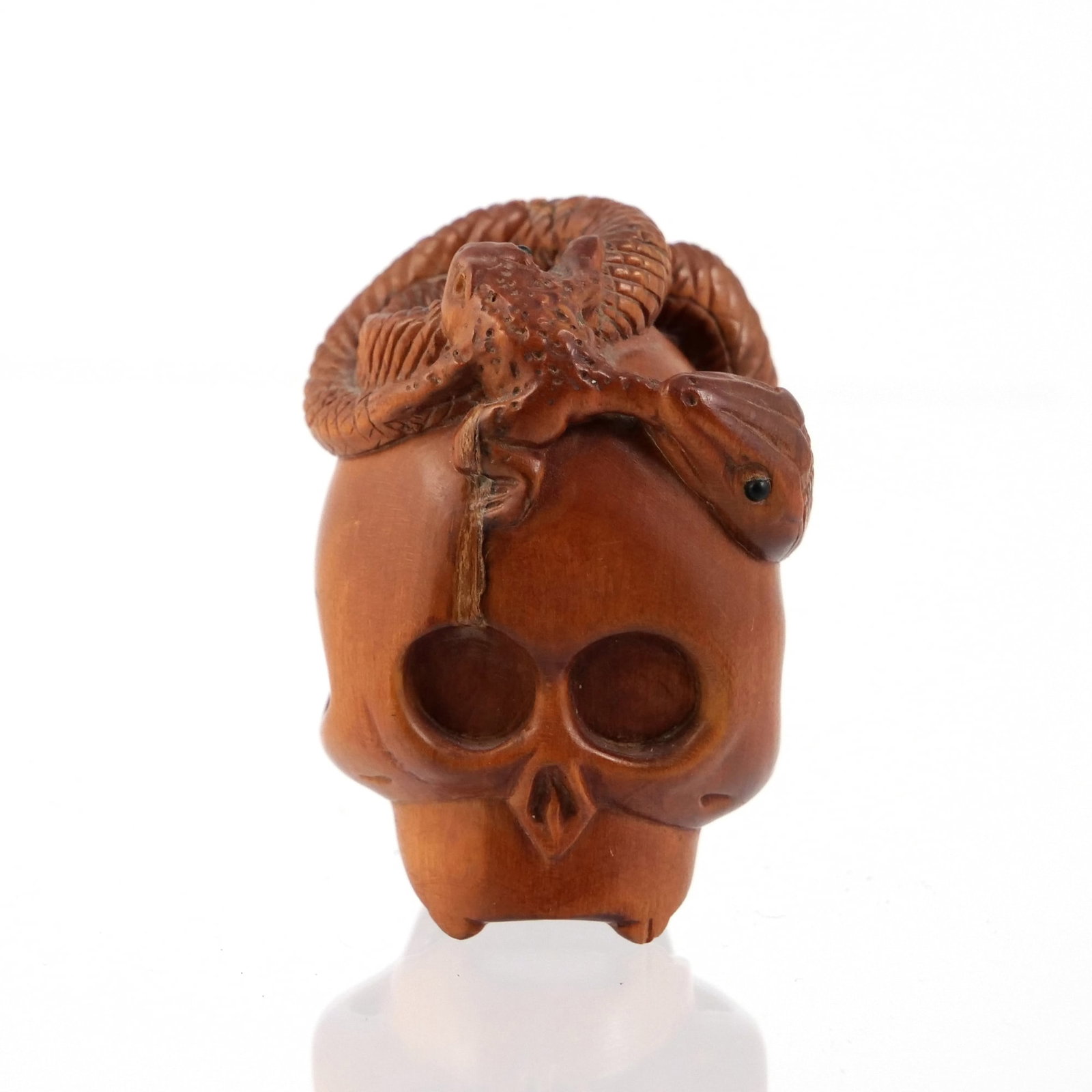 JAPANESE 'MEMENTO MORI' WOOD NETSUKE: Japanese netsuke likely carved from boxwood, depicting a skull with a snake coiled atop eating a frog, signed with marking to base - h. 2 in. Inventory No. 64-150 Provenance: Property from The