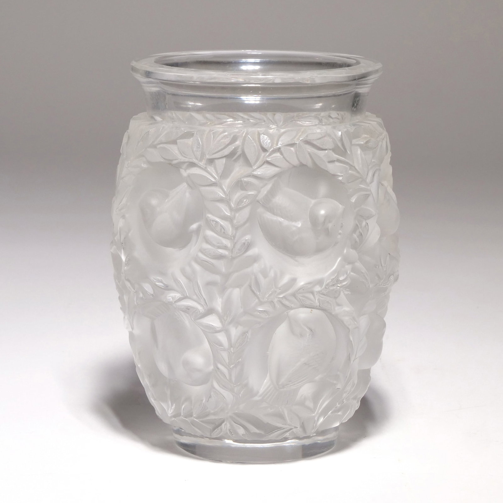 LALIQUE FROSTED AND CLEAR GLASS AVALLON VASE: Constructed of frosted and clear glass, featuring a repeating motif of birds positioned within circular medallions and surrounded by leafy foliage. The underside is signed "Lalique France." - h. 6.75 