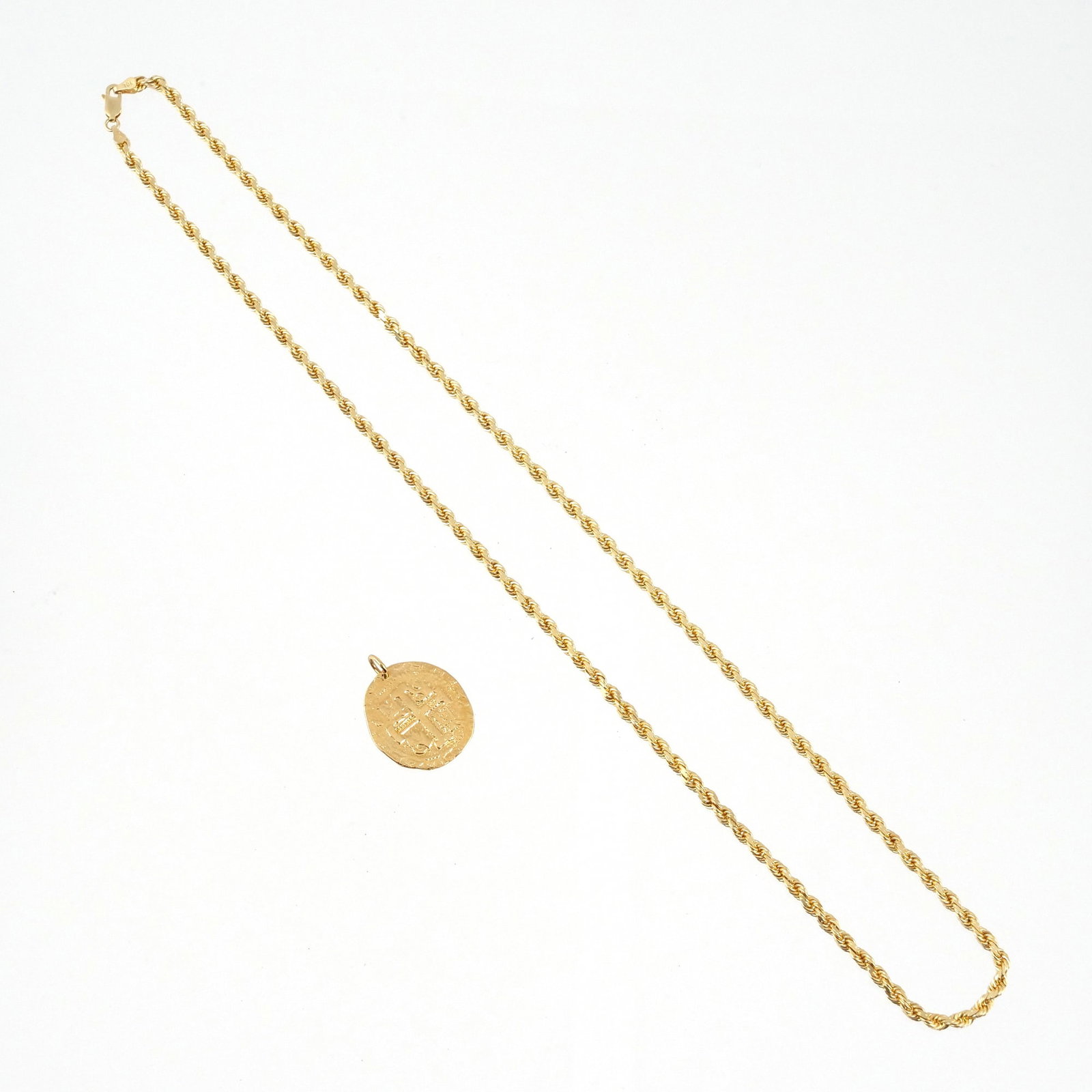 (2pc) 14K GOLD PENDANT & 10K GOLD CHAIN: A 14k gold coin-style pendant depicting a cross marked 'Bahamas 14k' on front (tested to 14k, approx. 1 in. long) with a 10k yellow gold rope link chain with fineness marks (23 in. long); total 14k we