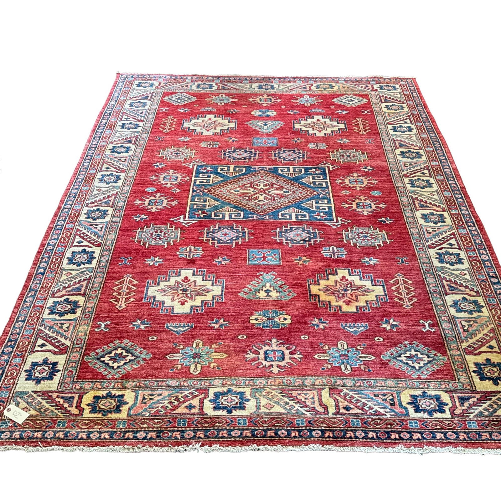 HAND-KNOTTED AFGHAN KAZAK WOOL PILE RUG: This hand-knotted wool rug features a central large geometric medallion on a red field surrounded by smaller tribal motifs. The composition is framed by multiple borders, including a primary cream bor