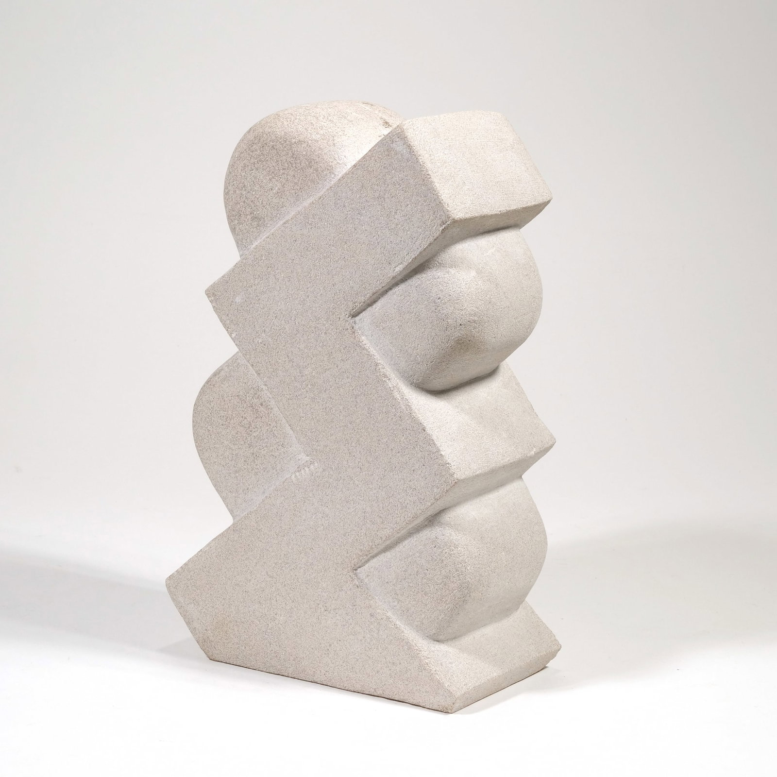 AMERICAN SCHOOL (20TH CENTURY) STONE SCULPTURE: untitled Carved stone h. 11.75 x w. 7.5 x d. 4 in. The sculpture features a vertical arrangement of interlocking geometric zig-zag forms contrasted with smooth, rounded bulbous elements. It is carved 