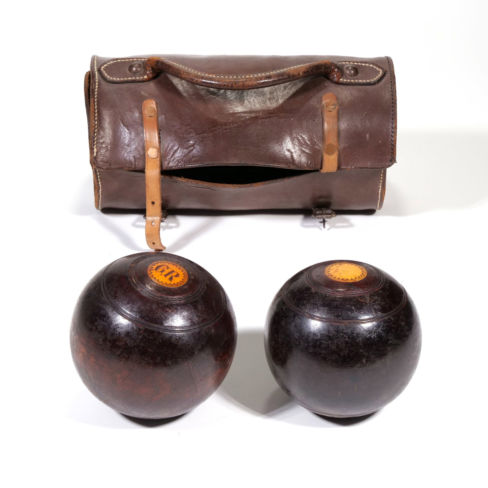 THOMAS TAYLOR GLASGOW LIGNUM VITAE LAWN BOWLS & LEATHER CASE: Set of two turned Lignum Vitae lawn bowls featuring circular yellow decorative inserts. One bowl is marked "THOMAS TAYLOR GLASGOW" and "No. 3 BIAS" while the other displays an engraved "GR" monogram. 