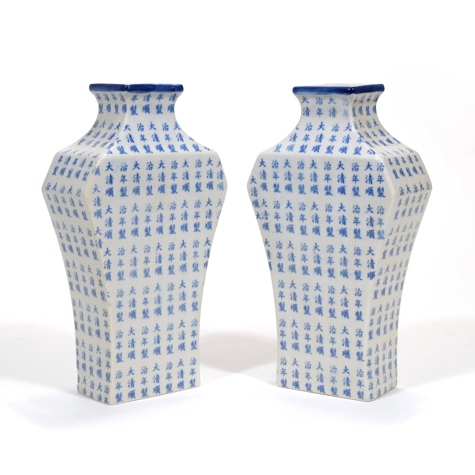 PAIR OF CHINESE BLUE AND WHITE PORCELAIN QUADRANGULAR CHARACTER VASES: A pair of porcelain vases featuring a quadrangular form with tapered bases and flared blue-lined rims. The white glazed bodies are decorated with a repeating pattern of underglaze blue Chinese