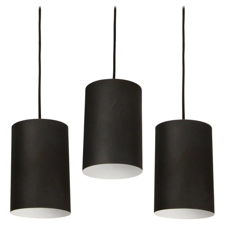 Set of 3 1950s Jo Hammerborg Pendants for Louis Poulsen: Quantity: 3 Set of 3 1950s Jo Hammerborg Pendants for Louis Poulsen. Executed in black painted cylindrical metal with custom patinated brass canopy and thick black cloth cord. Jo Hammerborg (Designer)