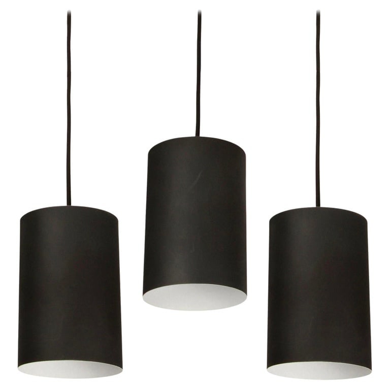 Set of 3 1950s Jo Hammerborg Pendants for Louis Poulsen: Quantity: 3 Set of 3 1950s Jo Hammerborg Pendants for Louis Poulsen. Executed in black painted cylindrical metal with custom patinated brass canopy and thick black cloth cord. Jo Hammerborg (Designer)