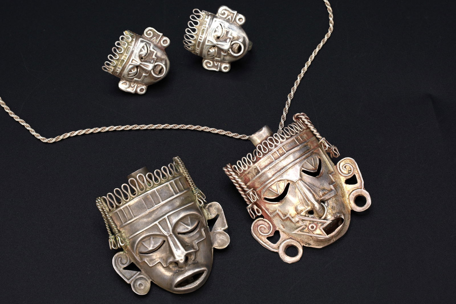 Taxco Mexico Jewelry Set, Art Deco Pendant Necklace, Brooch, Matching Earrings, Warrior Aztec Mask: Dimensions, Chain Length 20 inches, Pendant 1.75 x 1.65 inches, Brooch 1.75 x 1.65 inches, Earrings 0.8 x 1.0 inches. All measurements are approximate. Patina, Dings, General Wear And Aging. Sold As P