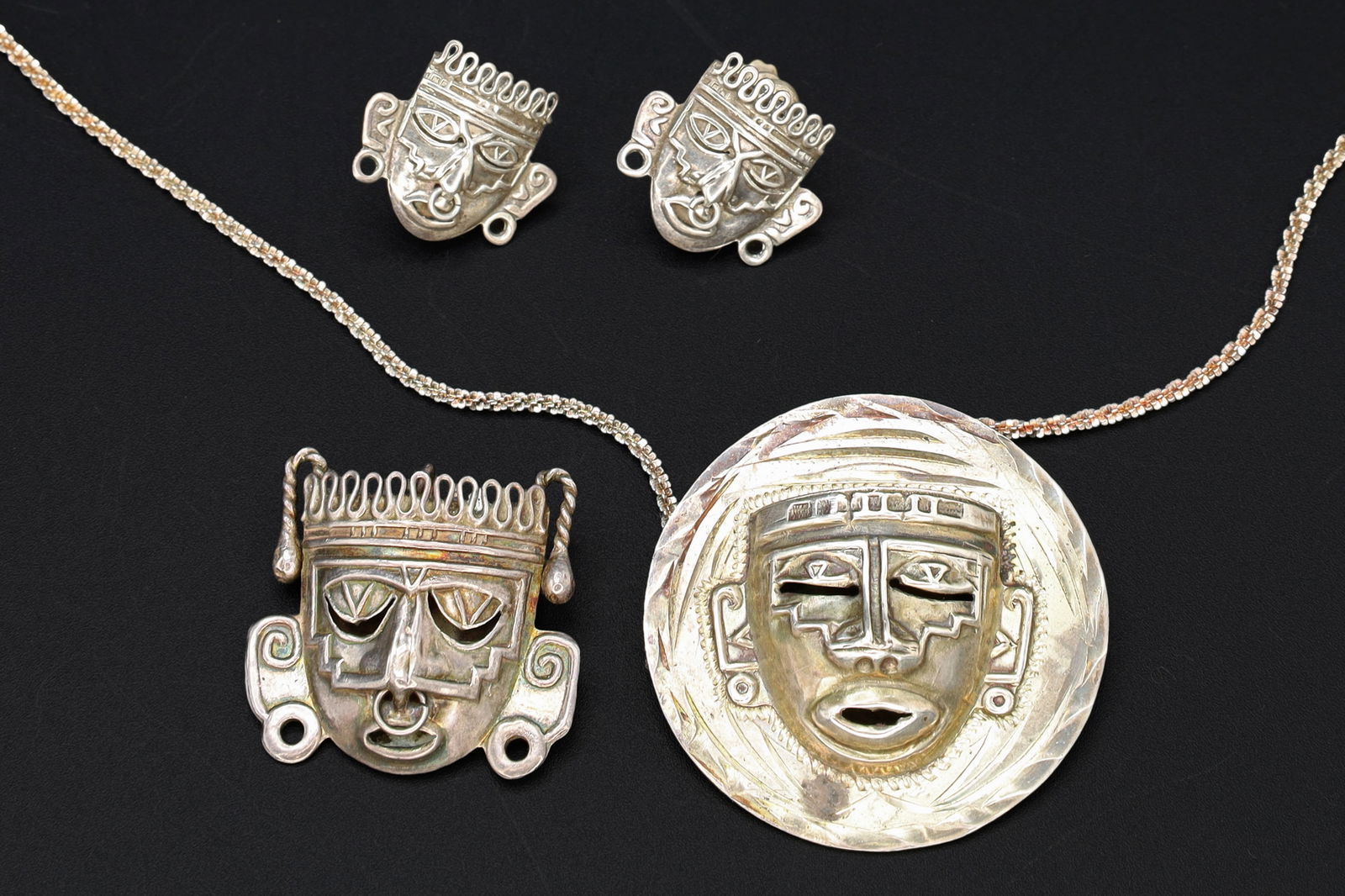 Taxco Mexico Jewelry Set, Art Deco Pendant Necklace, Brooch, Matching Earrings, Warrior Aztec Mask: Dimensions, Chain Length 19.5 inches, Pendant Diameter 1.55 inches, Brooch 1.125 x 1.2 inches, Earrings 0.75 x 0.75 inches. All measurements are approximate. Patina, Dings, General Wear And Aging. Sol