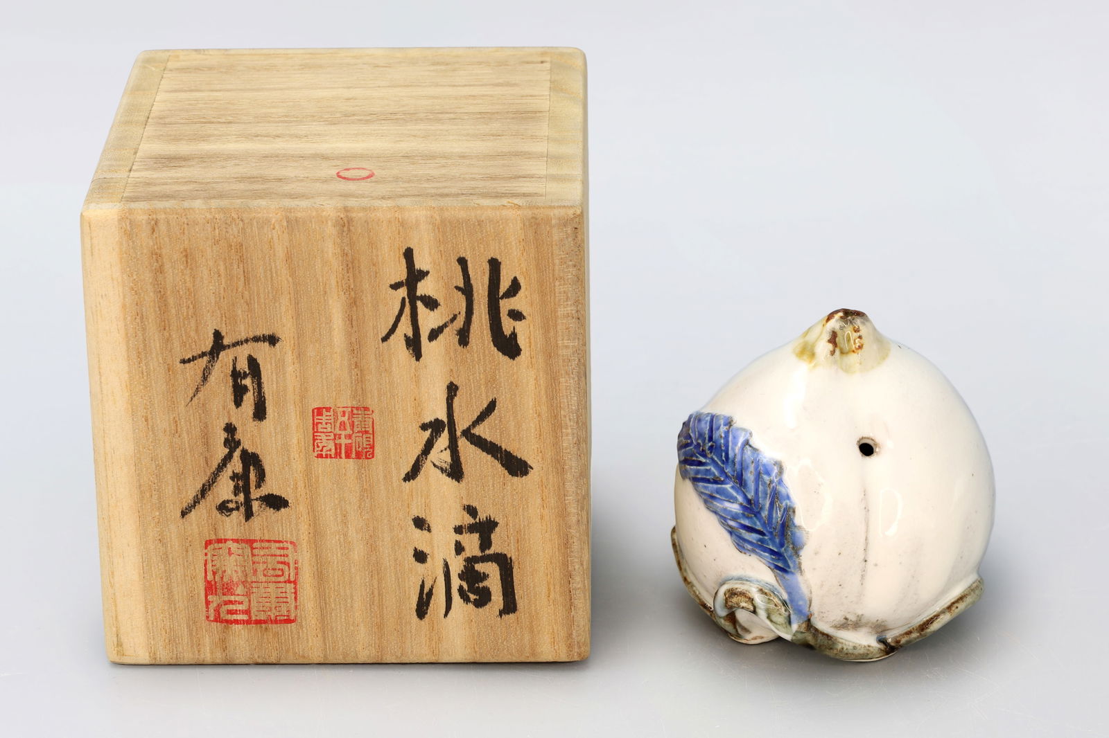 Ariyasu Takada, Suiteki Japanese Calligraphy Water Pot, Glazed Porcelain Shaped As A Peach: Ariyasu Takada, Suiteki Japanese Calligraphy Water Pot, Glazed Porcelain Shaped As A Peach. Stamp Of Maker At Bottom. KASAMA Ware Ceramics. In The Original Wooden Carrying Case. Condition As Shown In