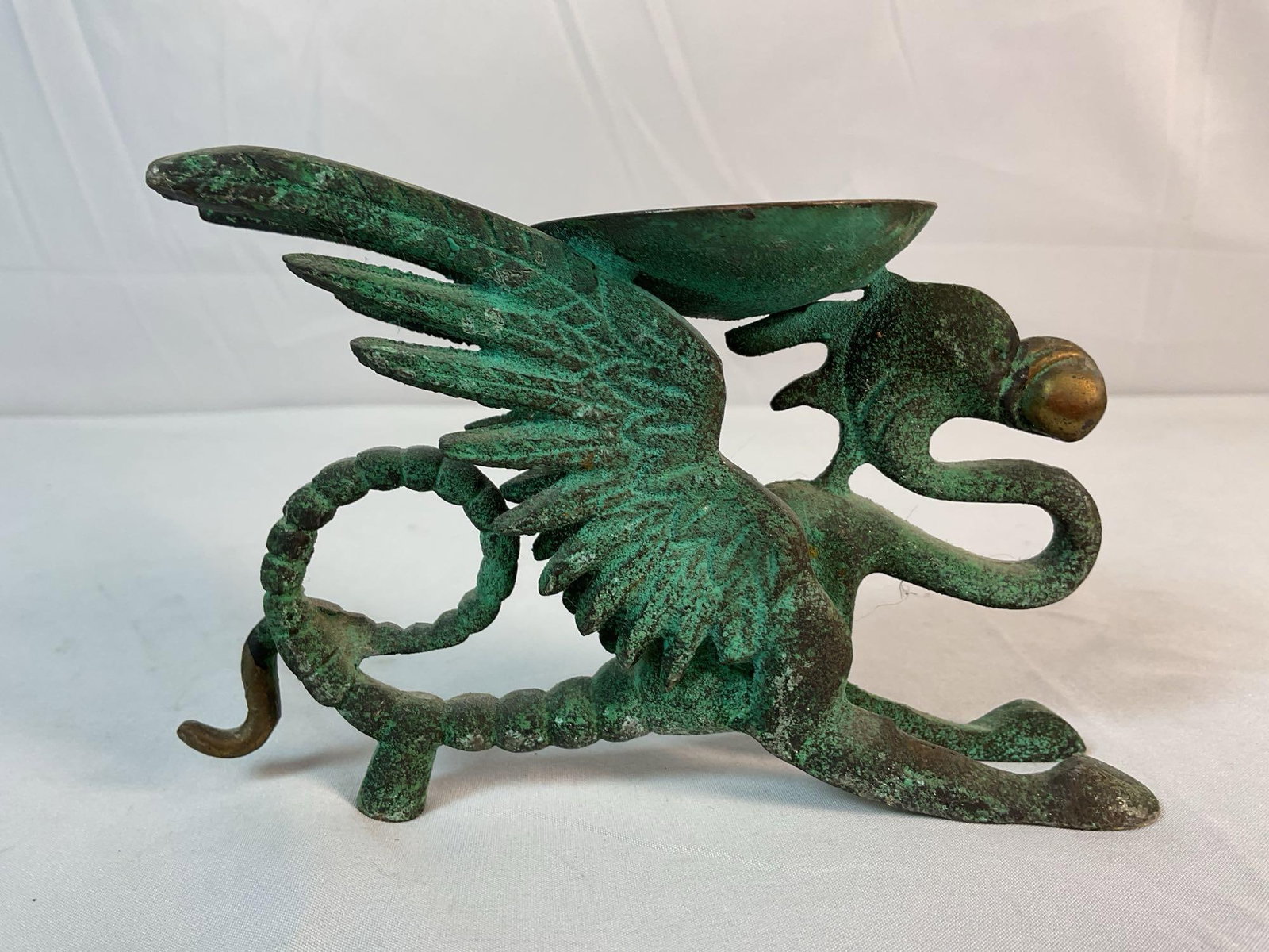Dragon Candle Holder: This striking bronze candle holder features a fierce, winged dragon in a crouching stance, mouth open as if ready to strike. The dragon's tail coils dramatically, forming a sturdy base, while its wing