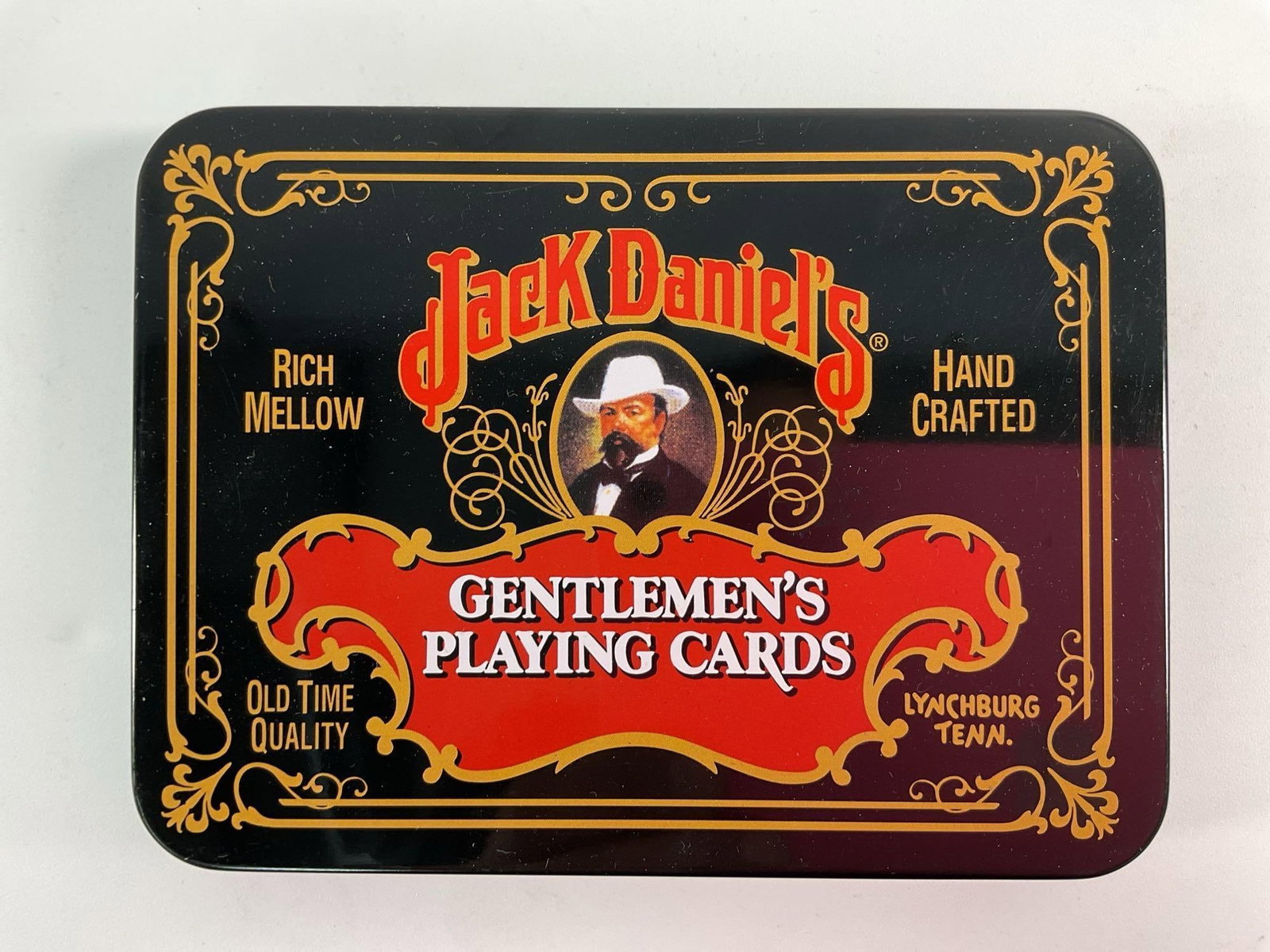 "Jack Daniel's Gentlemen's Playing Cards in Collectible Tin": This set of Jack Daniel's Gentlemen's Playing Cards is presented in a stylish collectible tin. The tin features a vintage design with bold red and black accents and the iconic Jack Daniel's branding. 