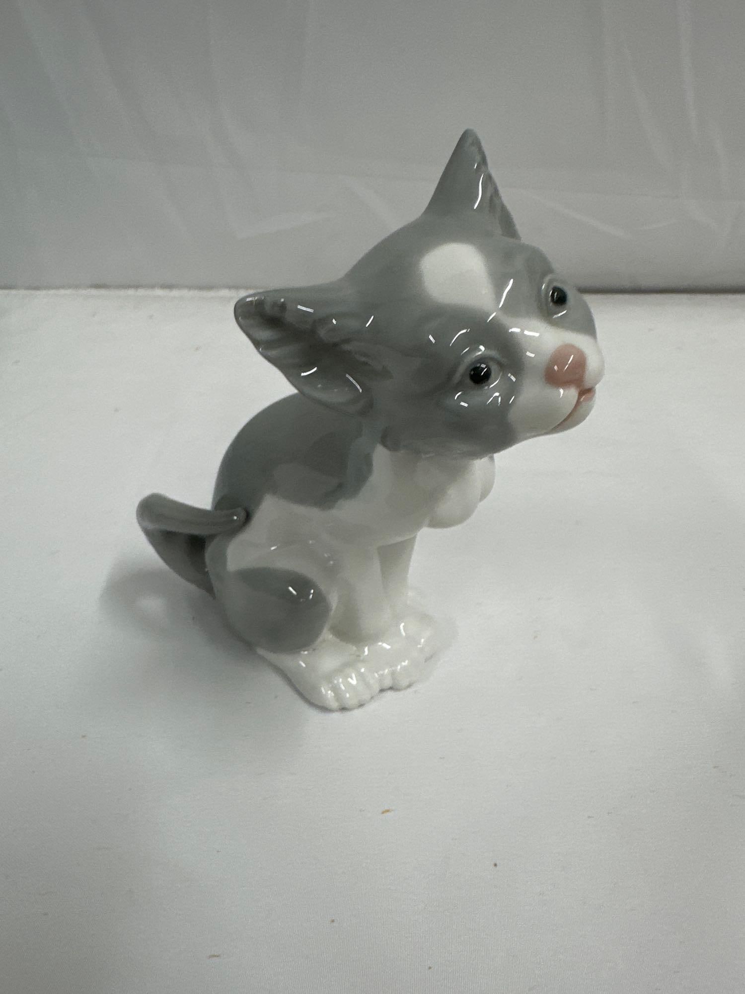 Lladro Porcelain Figurine "Feed Me" Model 5113 – Sitting Gray & White Kitten: This Lladro porcelain figurine features an adorable gray and white kitten, sitting attentively with an inquisitive expression. The figurine showcases delicate hand-painted details, with a glossy finis