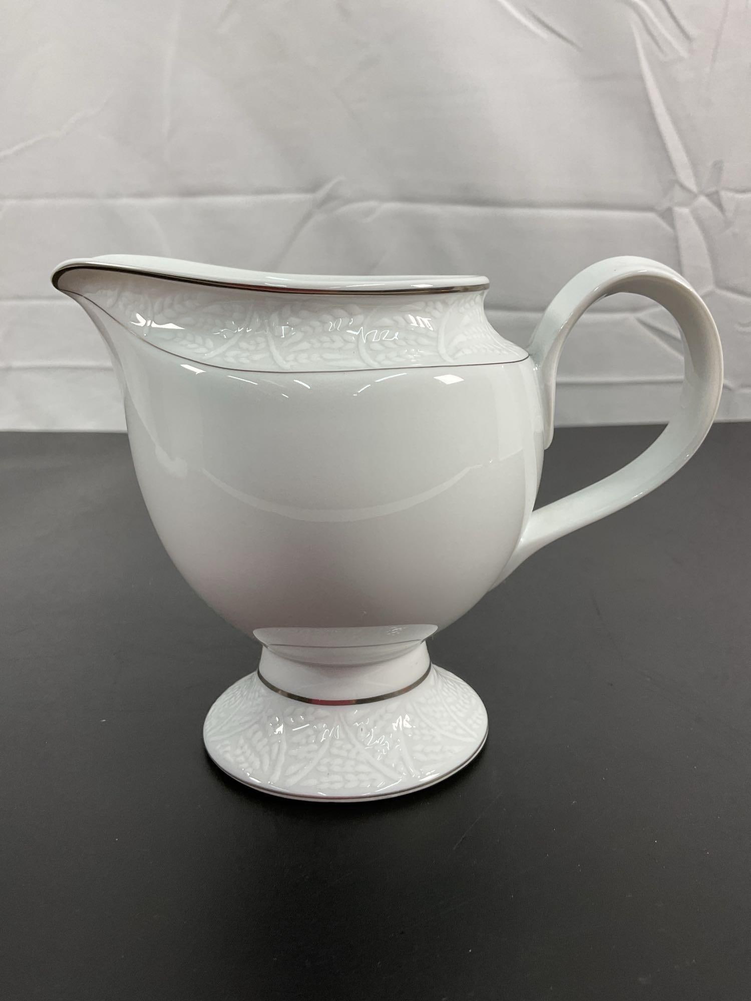 Lalique Limoges Porcelain Creamer: An elegant set featuring a fine Limoges porcelain creamer crafted by Lalique. This piece displays refined craftsmanship, characterized by a delicate embossed leaf motif, subtly accentuated by silver-t