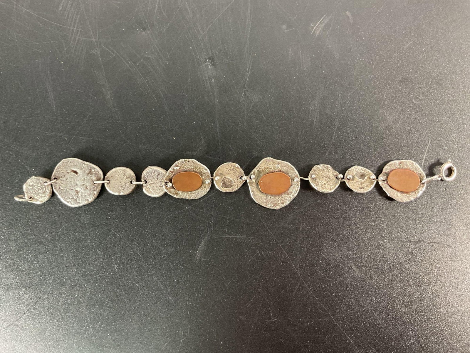 Artisan Sterling Silver and Carnelian Textured Link Bracelet: This is a handcrafted sterling silver link bracelet featuring textured, organic-shaped silver links interspersed with oval carnelian cabochon stones. The hammered or reticulated finish gives it a rust