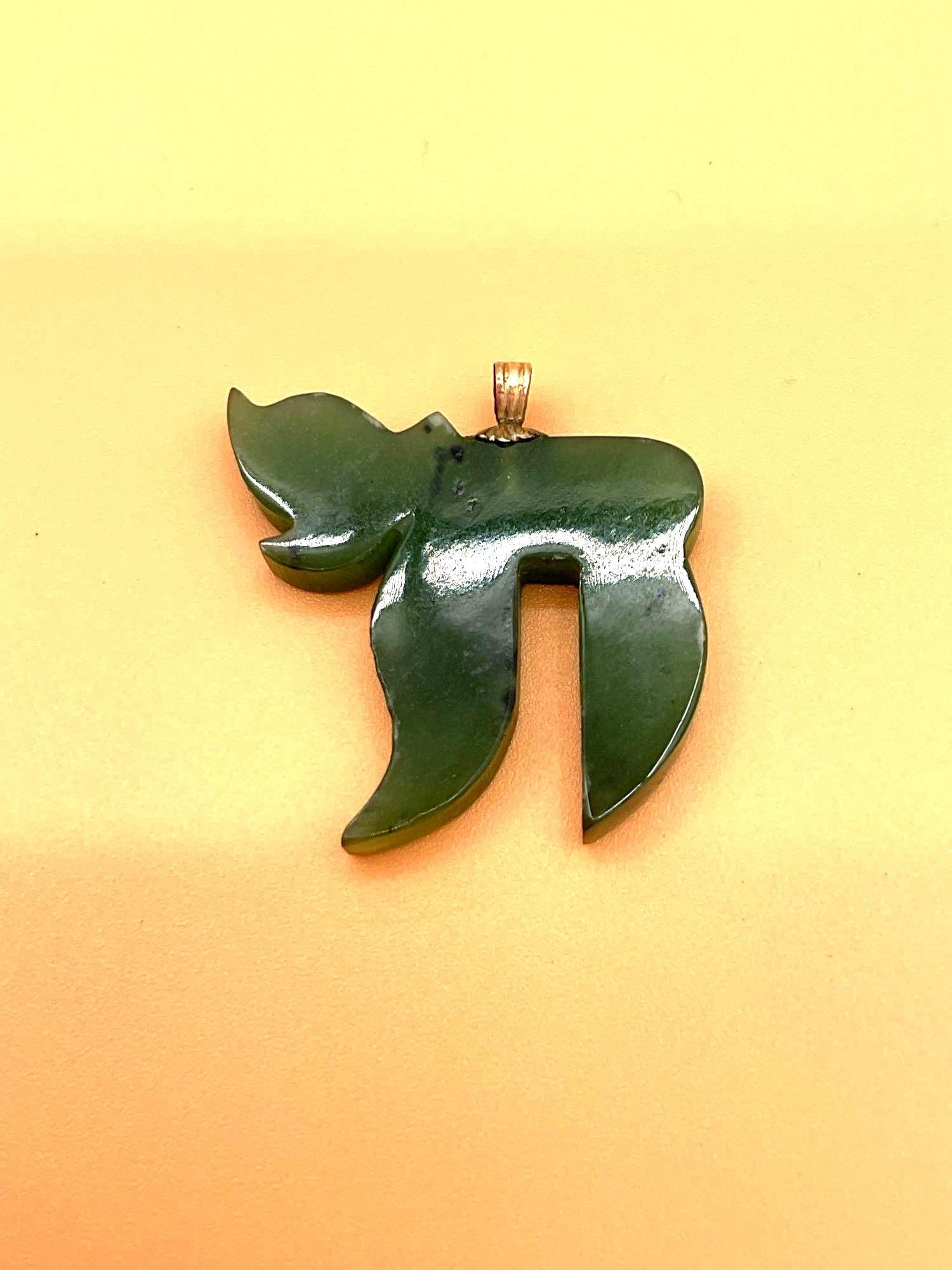 Jade Chai Pendant with Gold Bail: This is a pendant carved in the shape of the Hebrew word “Chai” (??), which means "life" in Hebrew and is a popular symbol in Jewish culture. The piece appears to be made of polished g