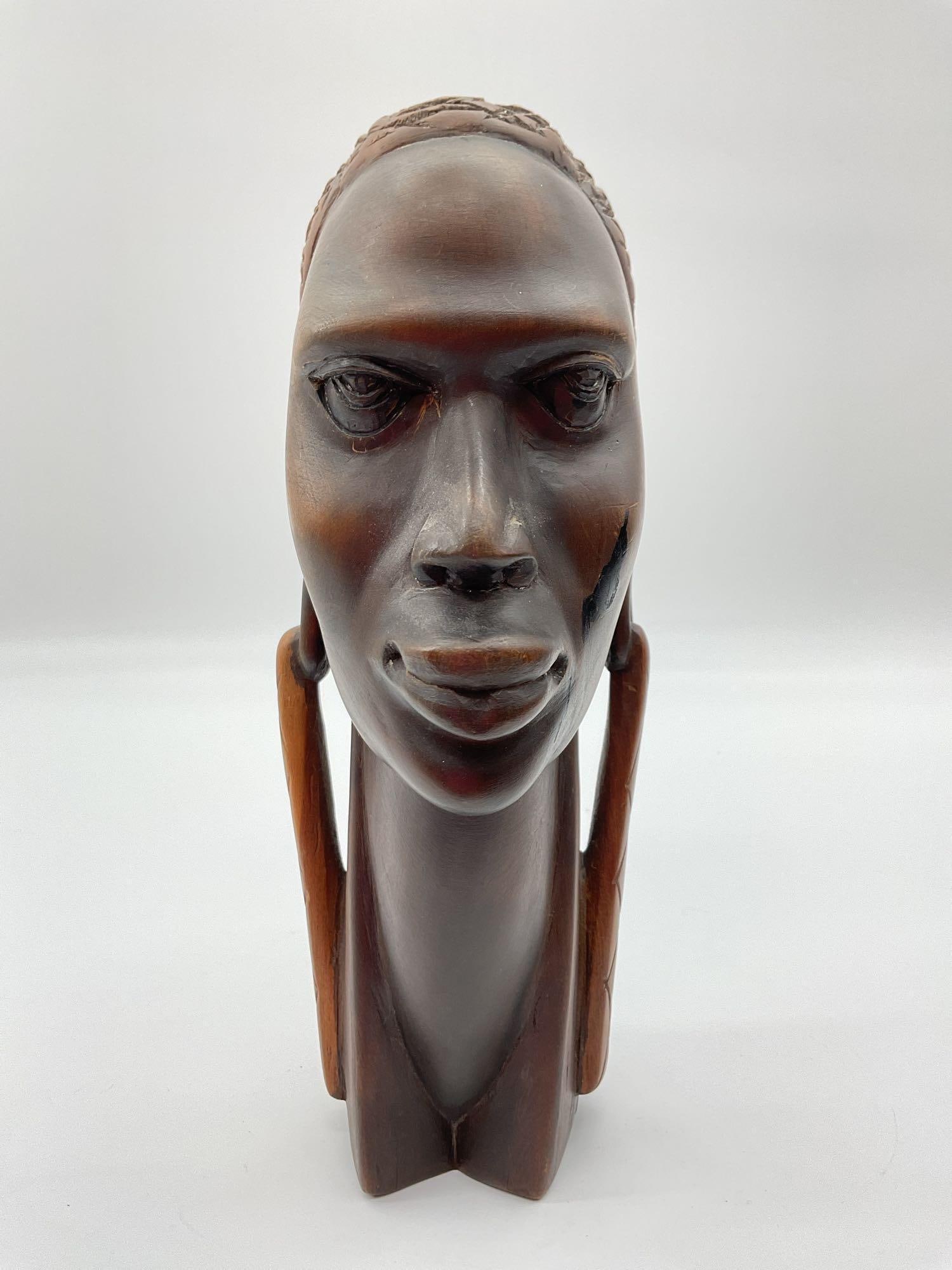 African Hand-Carved Hardwood Bust of a Woman: This elegant wooden bust portrays a woman with elongated features, expressive eyes, and a calm, confident expression. Her elongated neck and stylized earrings add a sculptural grace, while the smooth 
